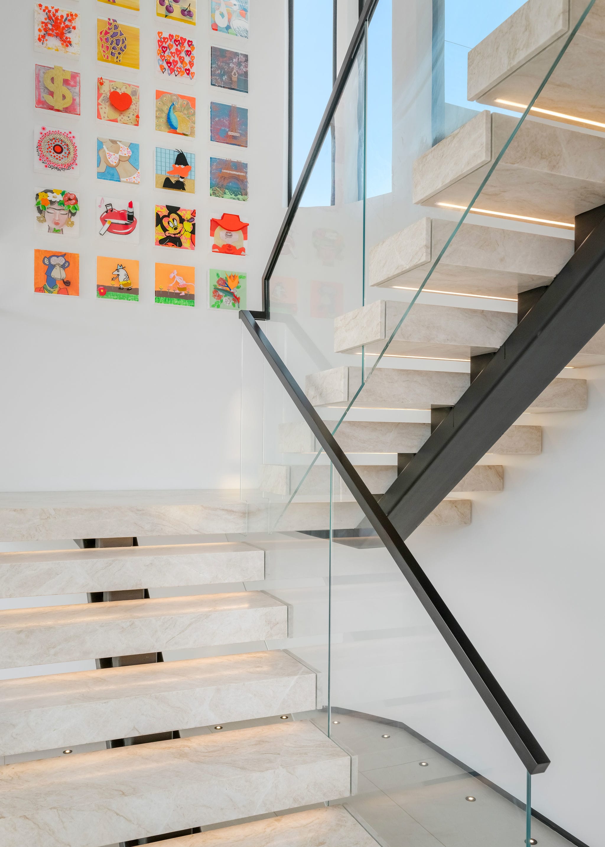 Floating staircase with glass railing and curated gallery wall.