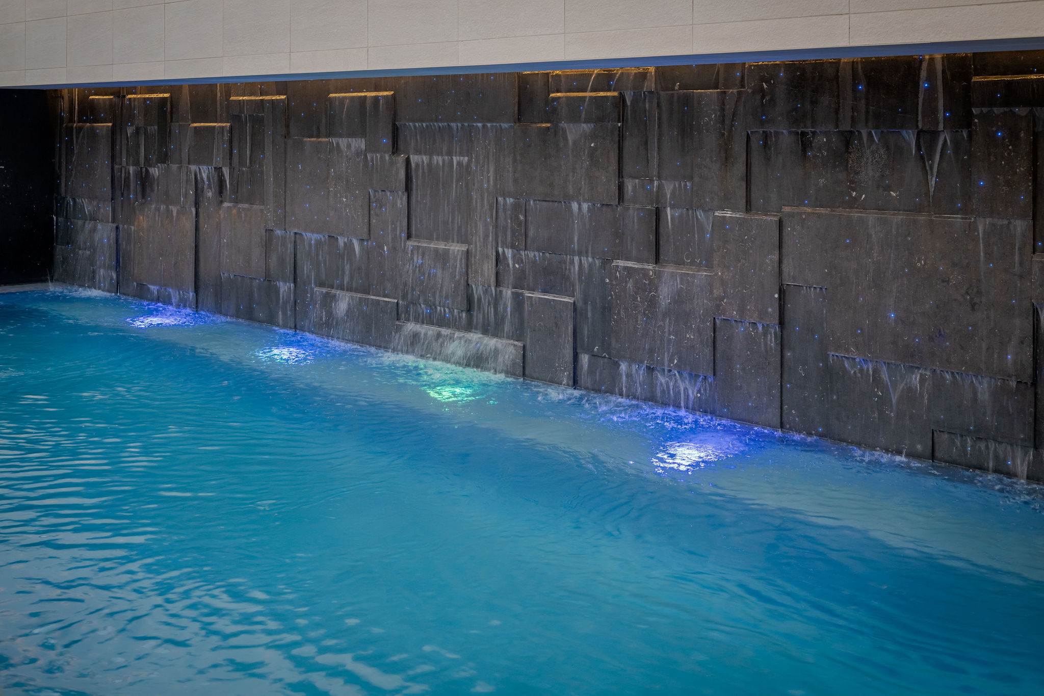 Follow the length of the water feature, lit and running alongside the pool.