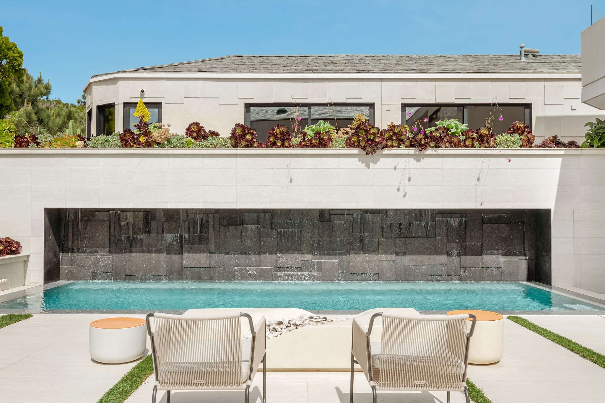 Architectural courtyard with water-wall feature and resort-style lounge seating.
