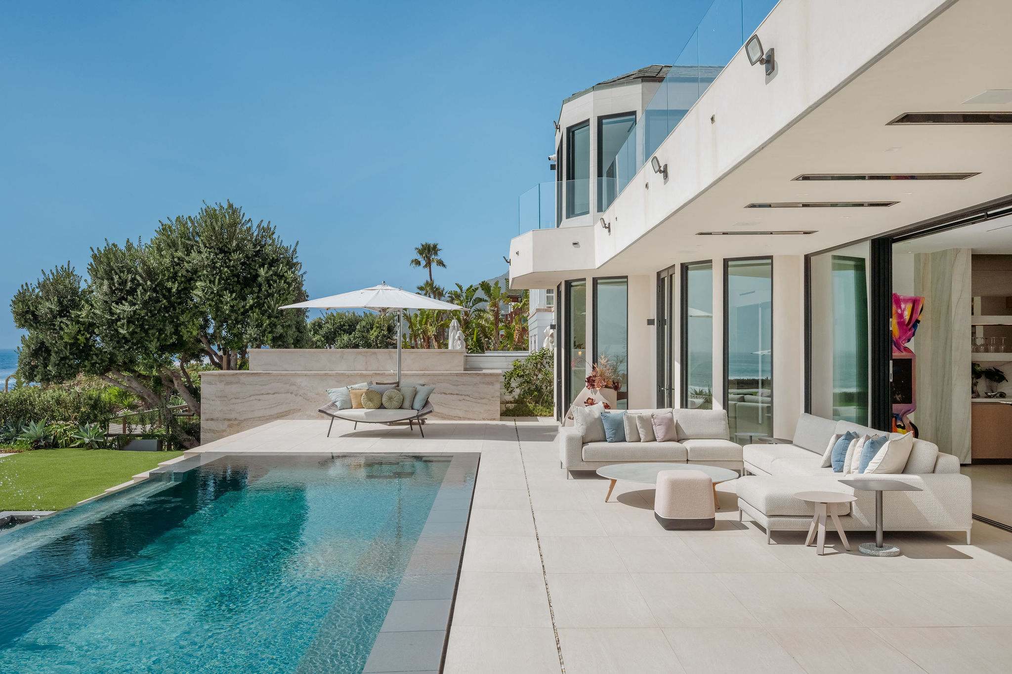 Infinity-edge pool with oceanfront terrace and lounge seating.