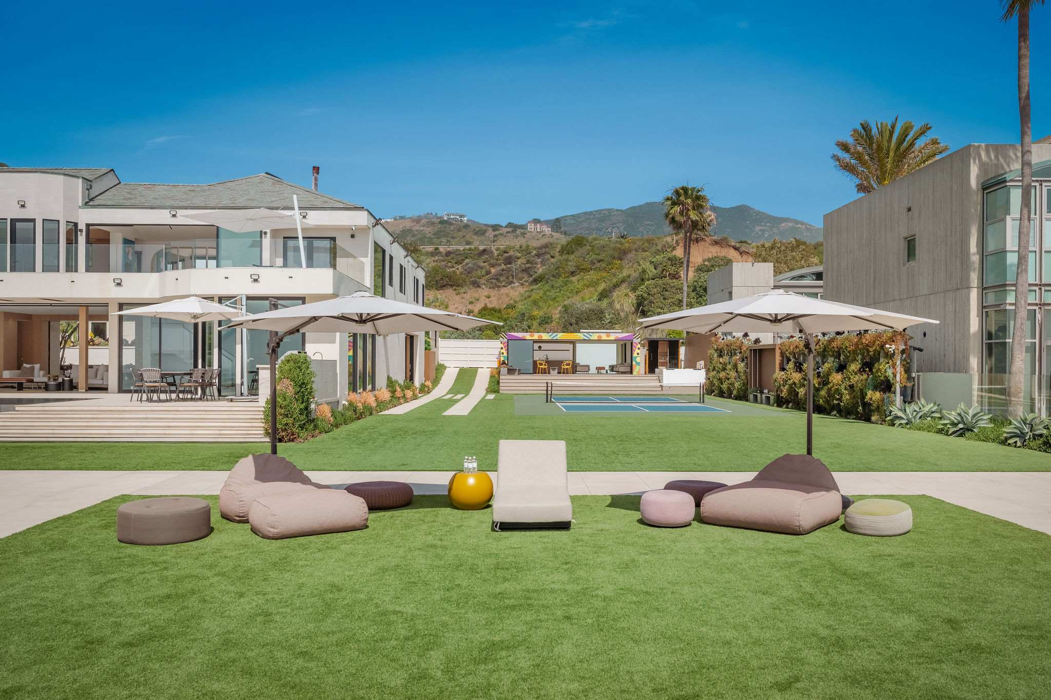 Expansive Malibu backyard with lounge pods, open lawn, and full estate backdrop.