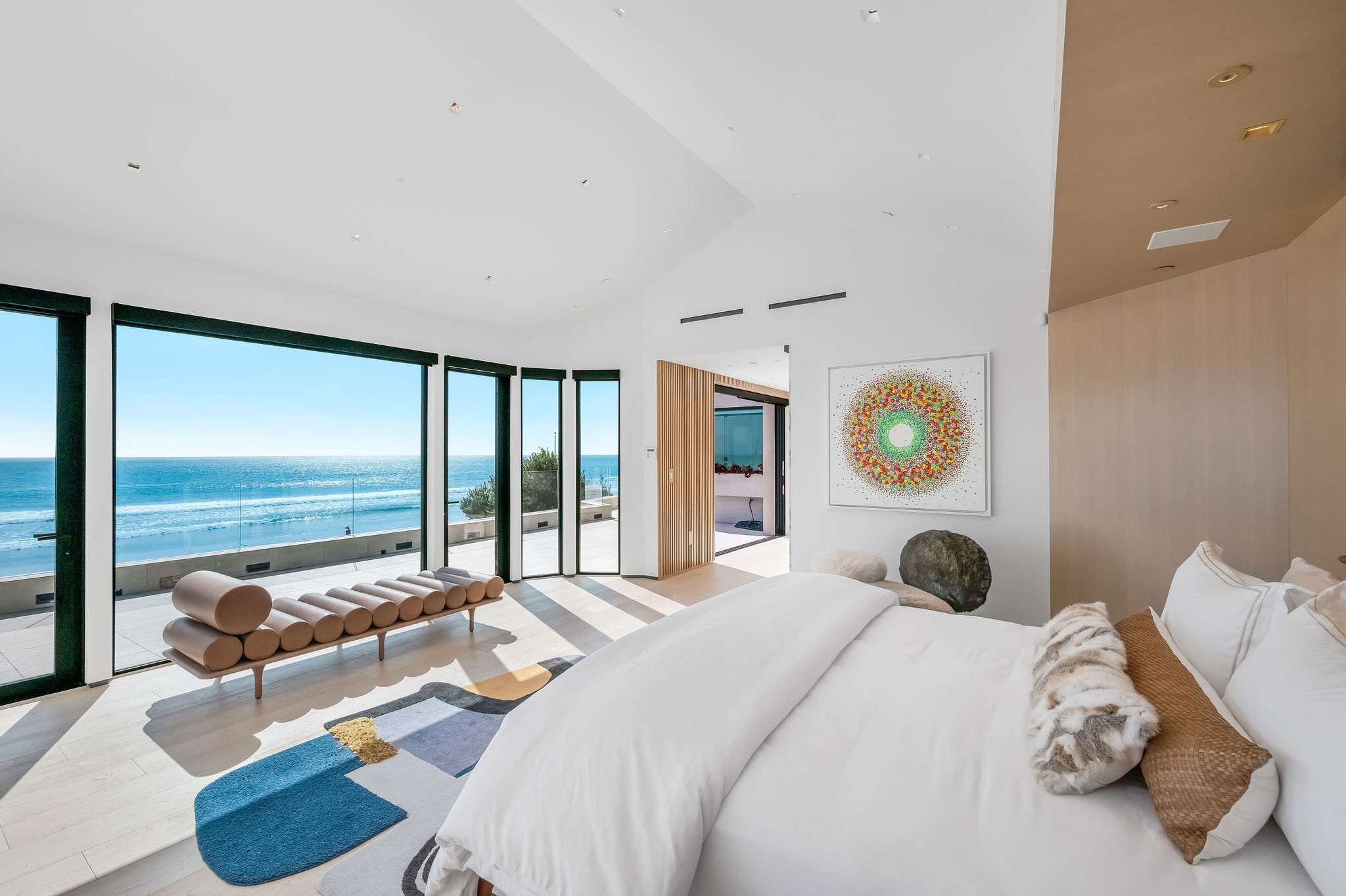 Oceanfront bedroom with floor-to-ceiling glass and uninterrupted Pacific views.