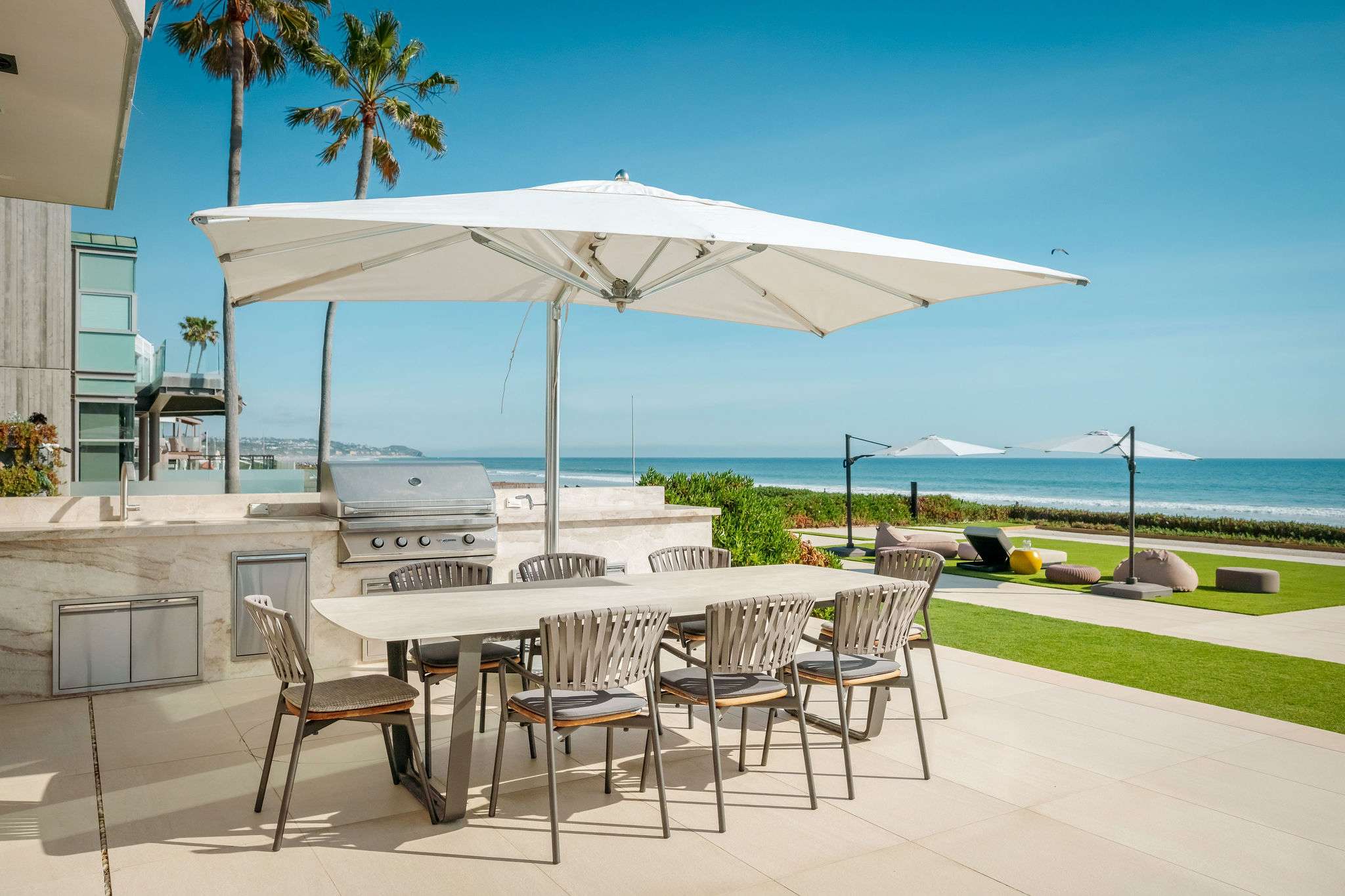 Oceanfront outdoor dining with shaded seating and direct beach access.