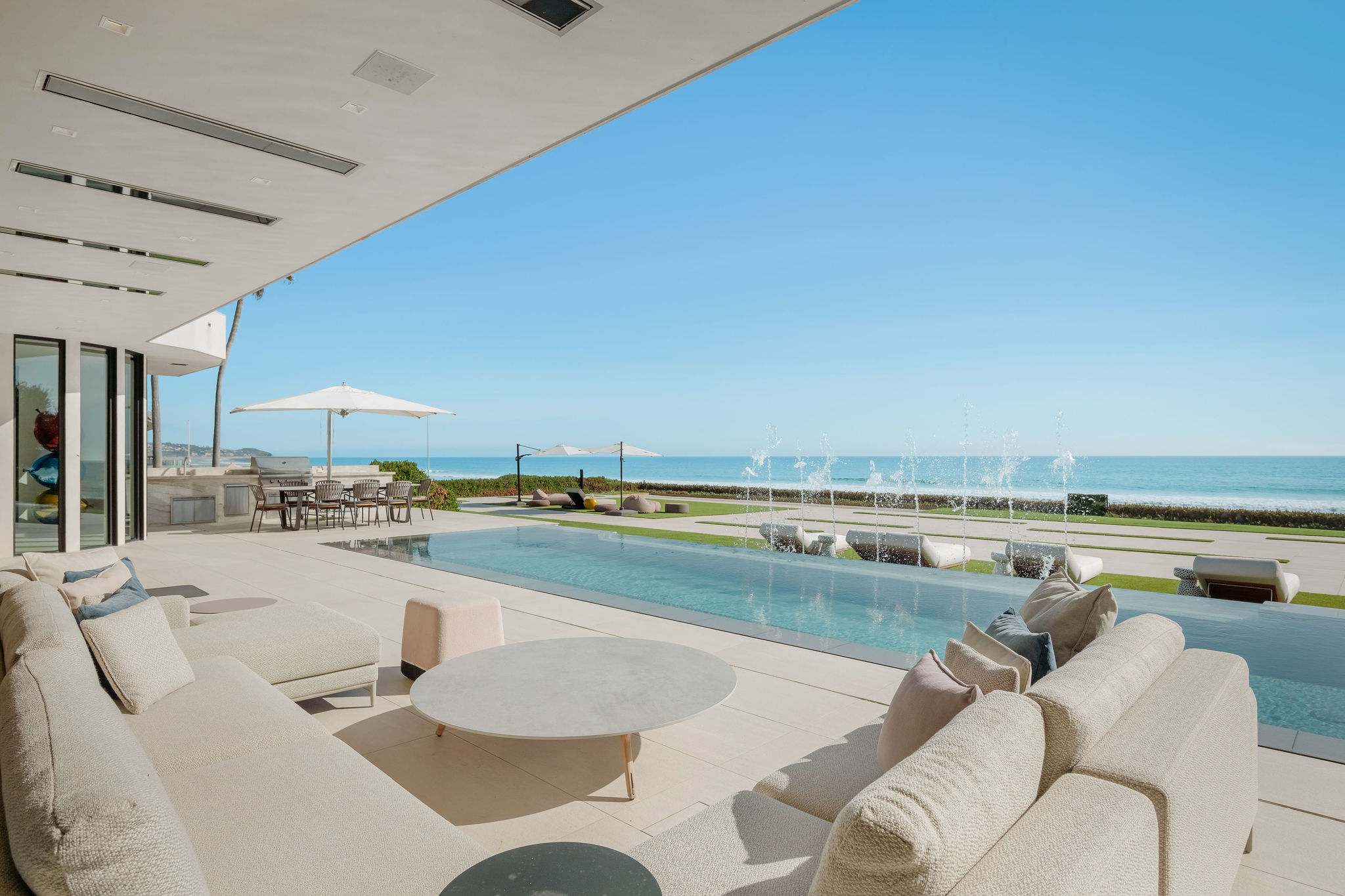 Covered oceanfront lounge overlooking infinity-edge pool and Malibu coastline.