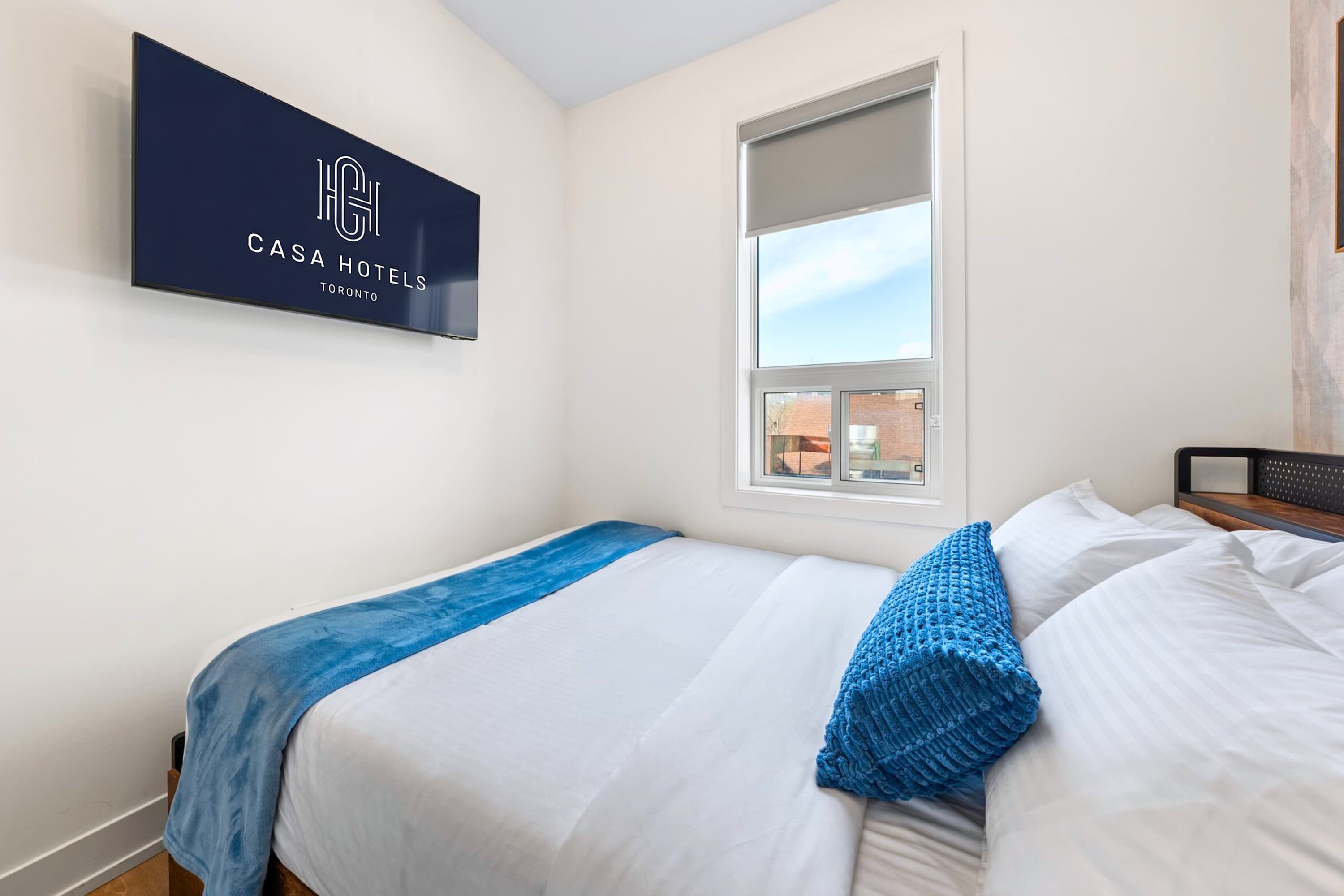 Cozy bedroom with Smart TV, large window and city views.