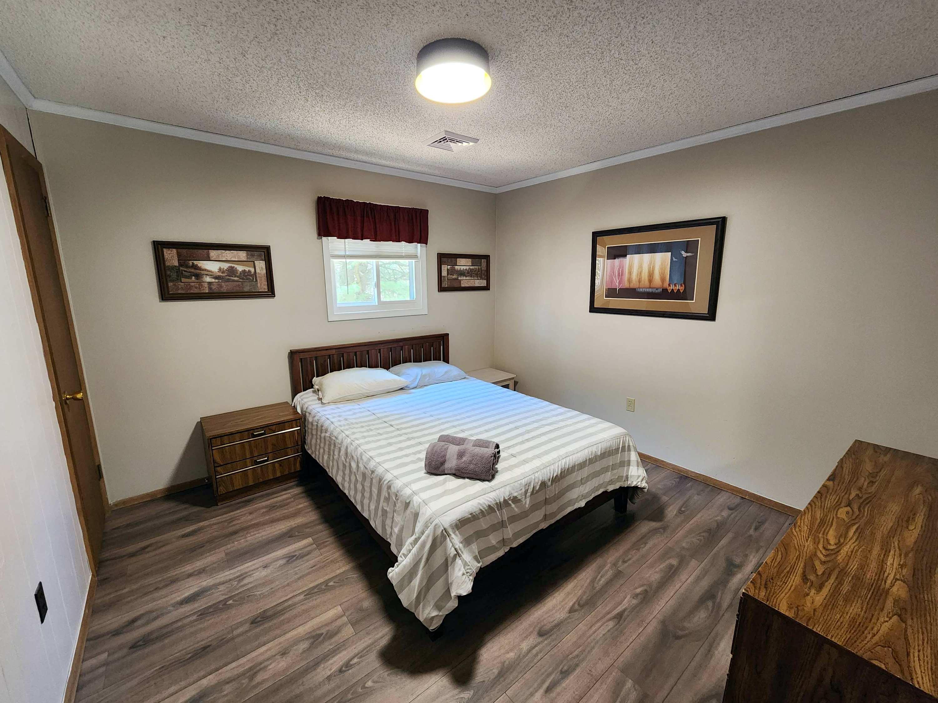 A restful bedroom with warm wood paneling and a ceiling fan for comfort