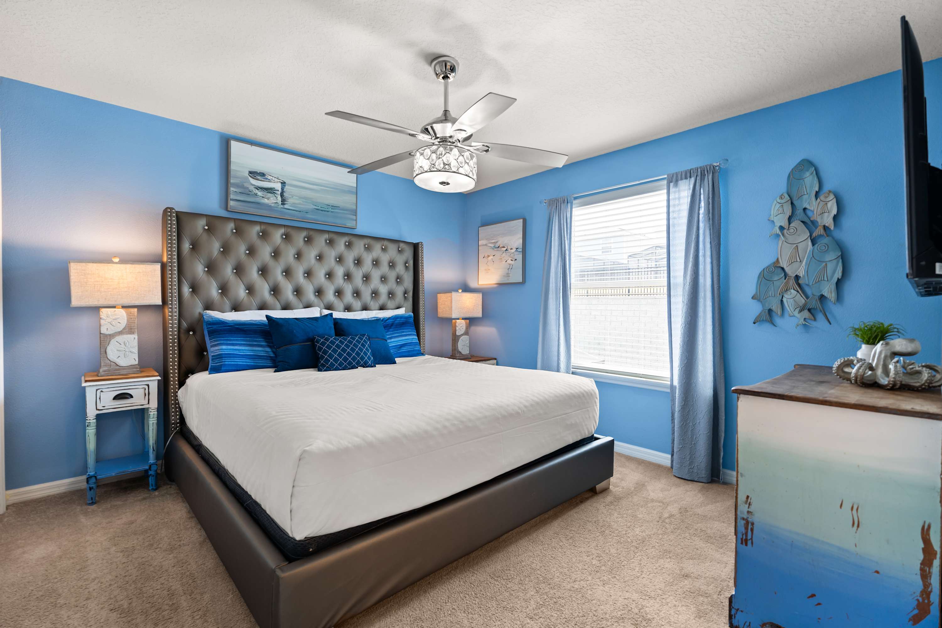 Ocean-inspired bedroom with king bed, headboard, bedside lamps, and ceiling fan for cozy comfort