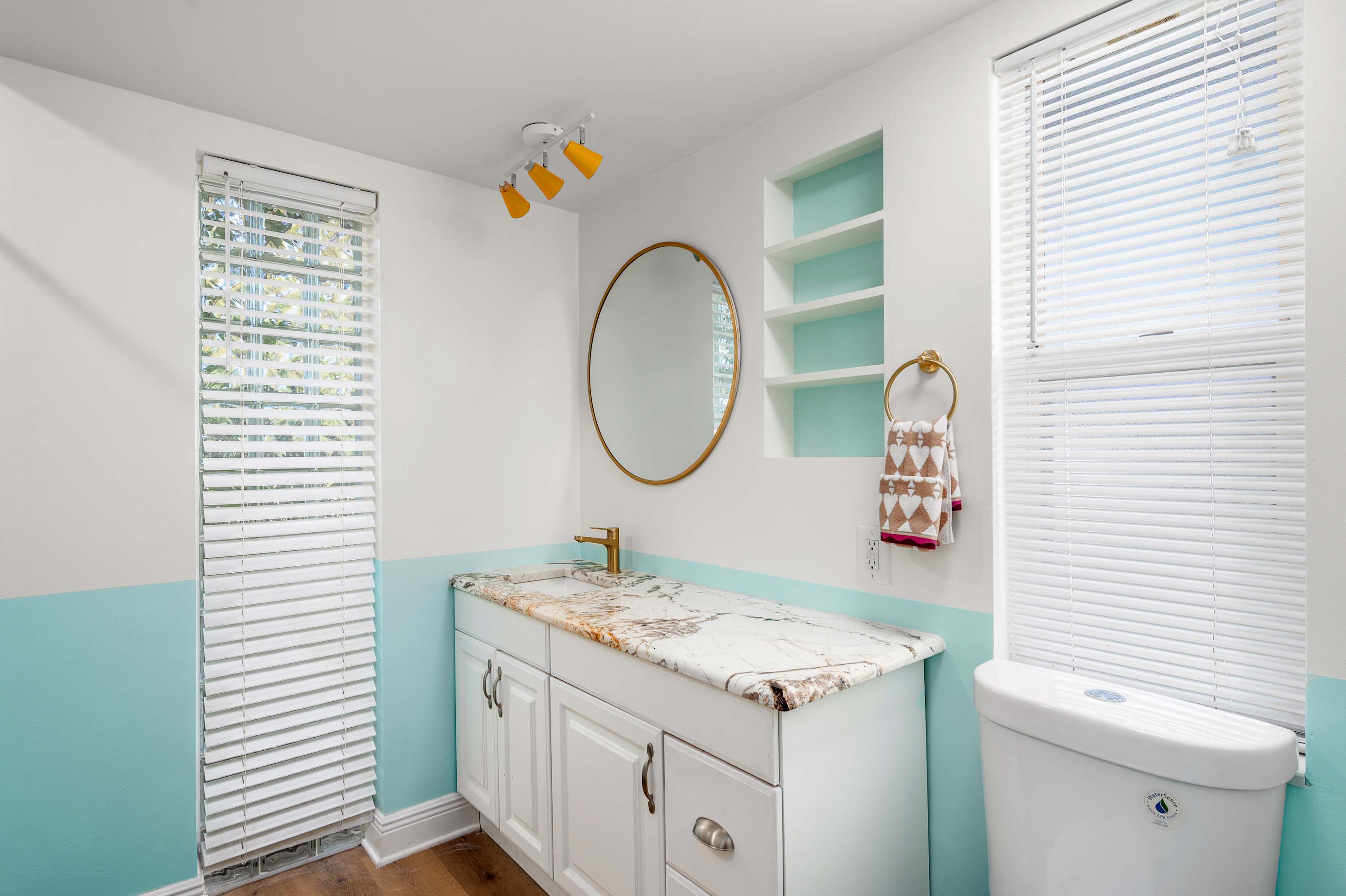 Bright bathroom with marble countertop and round mirror