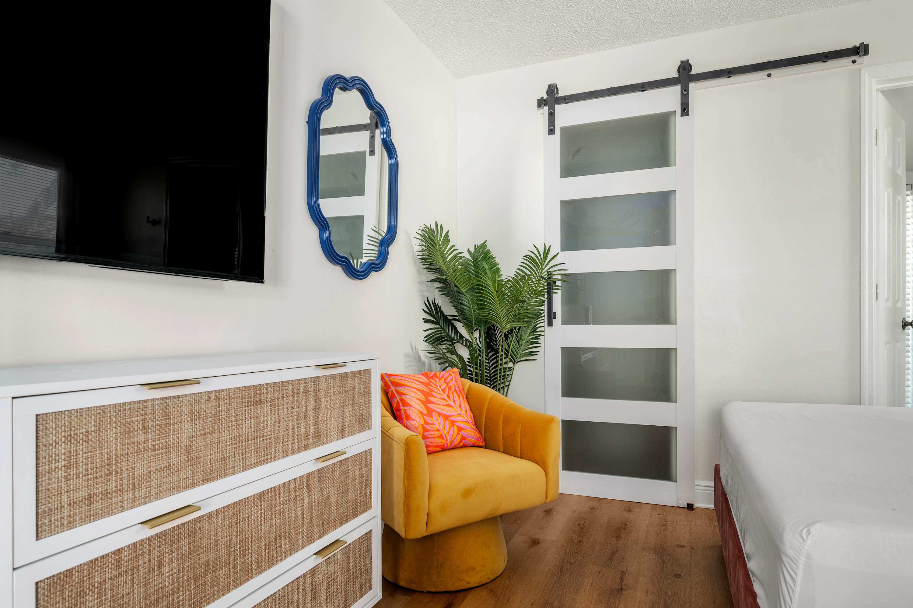 Modern bedroom corner featuring a sliding barn door, vibrant armchair, and textured dresser.
