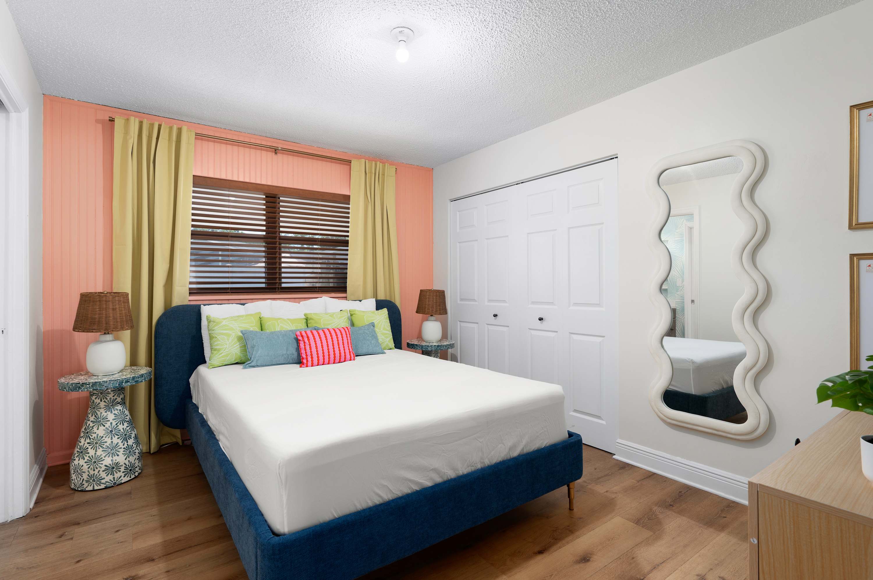 Cozy bedroom with a blue upholstered bed and a decorative mirror on the wall