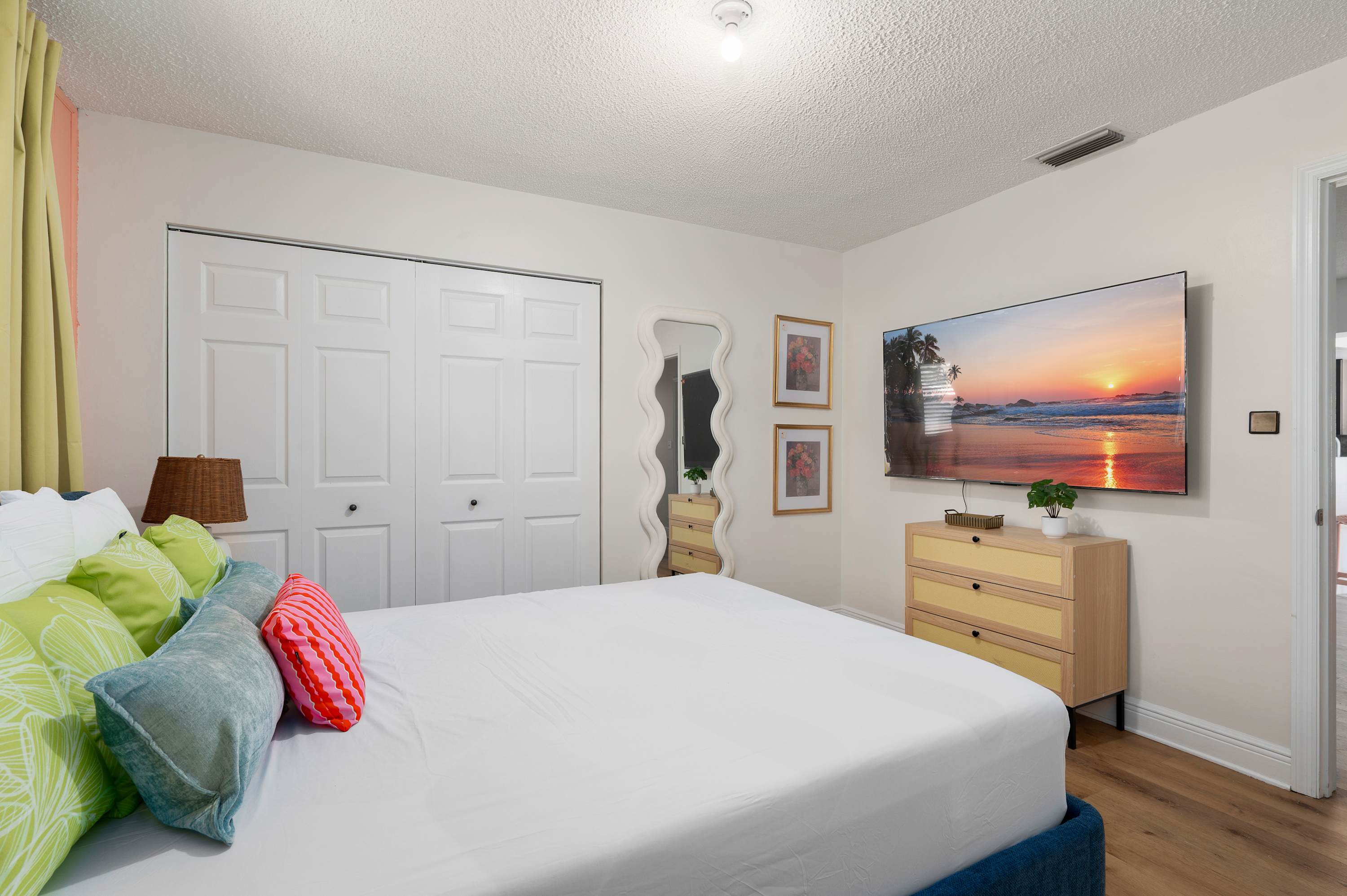 Relax in this bright bedroom featuring a large wall-mounted television and ample closet space.