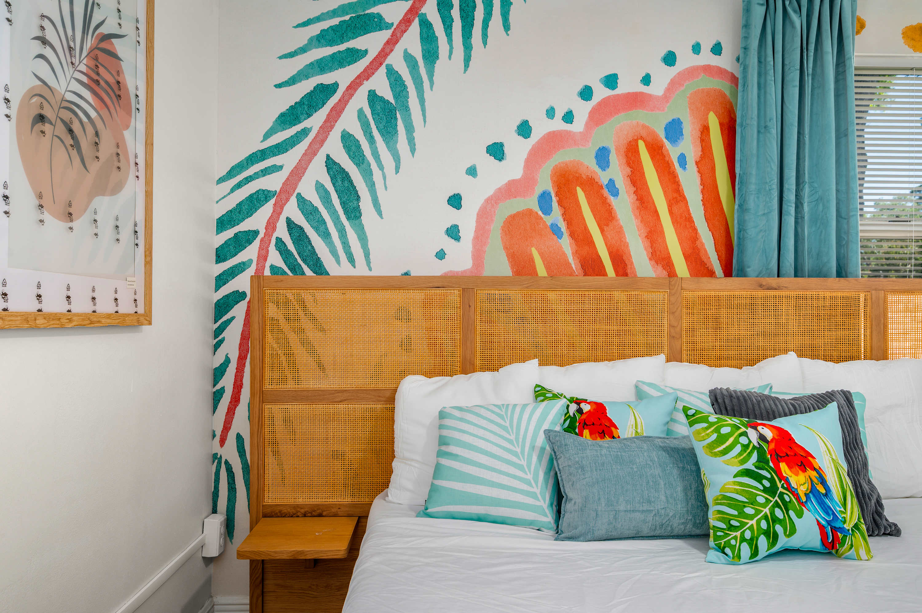 Tropical-themed bedroom with colorful pillows and a rattan headboard.