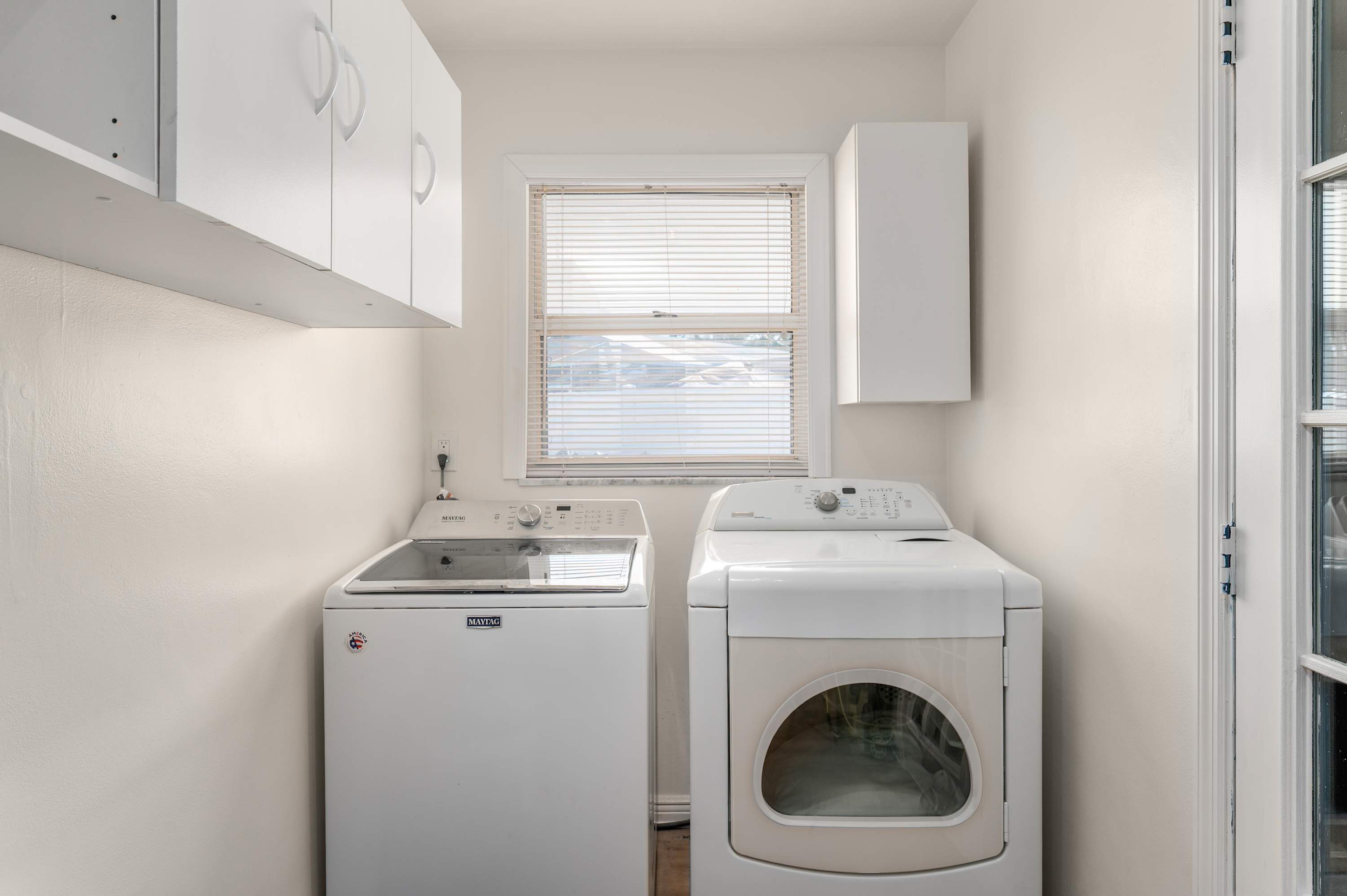 Laundry room with washer, dryer, and overhead storage cabinets