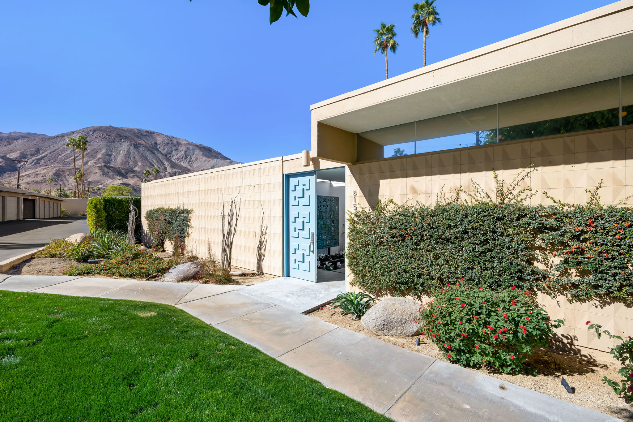 Front exterior with a blue gate, lawn and mountain backdrop.