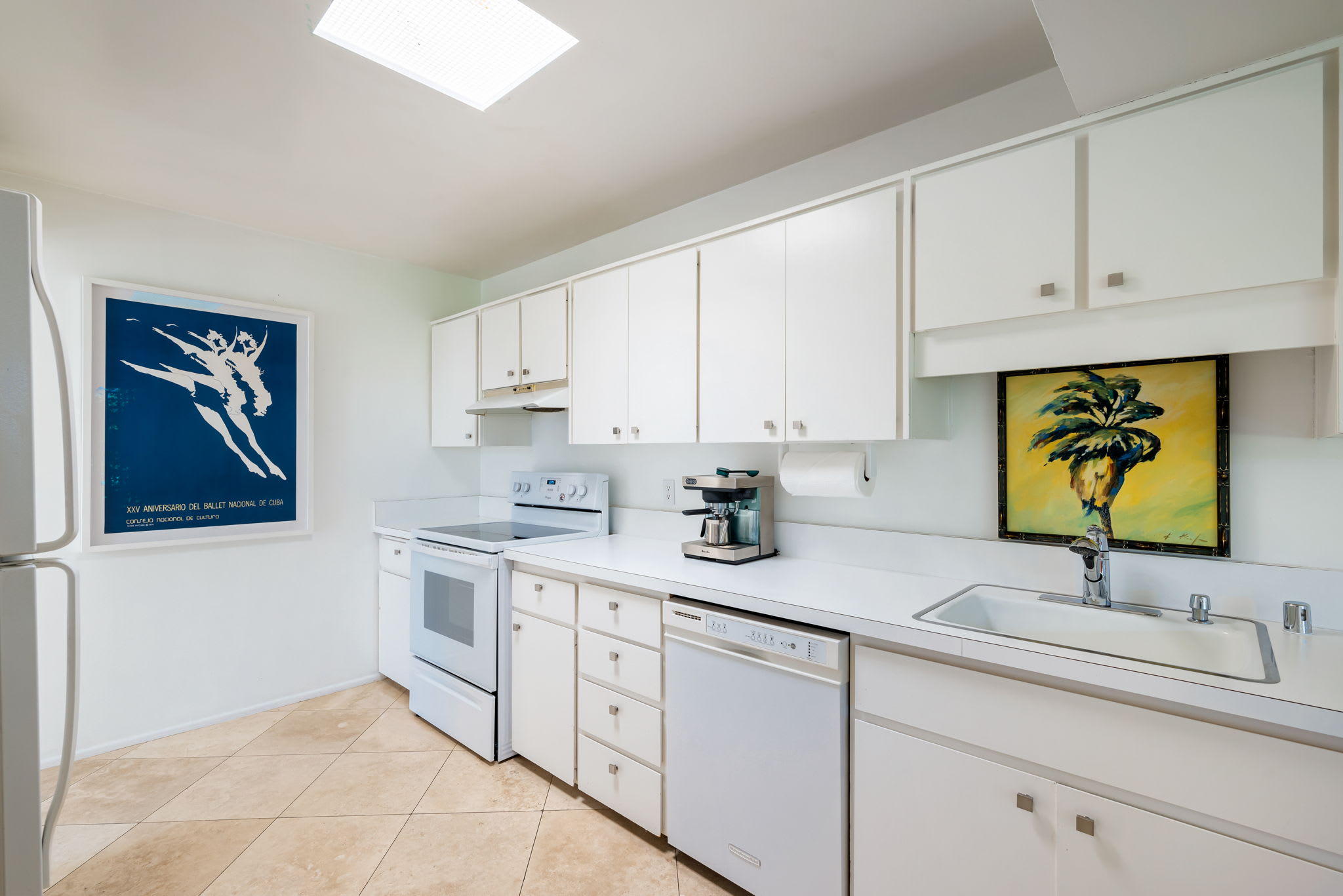 Kitchen sink and worktop beneath a window, with white cabinets.