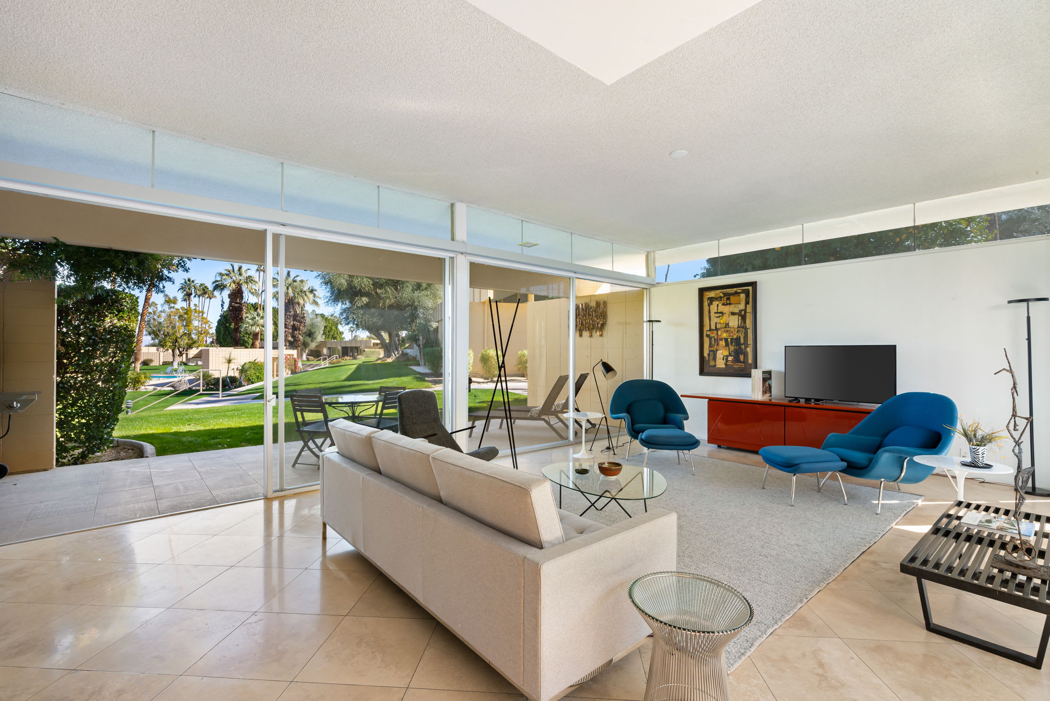 Open living room with a white sofa and blue chairs facing the garden.