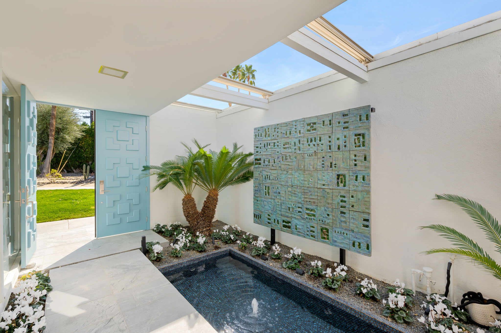 Front courtyard with a water feature, planting and patterned block screen.