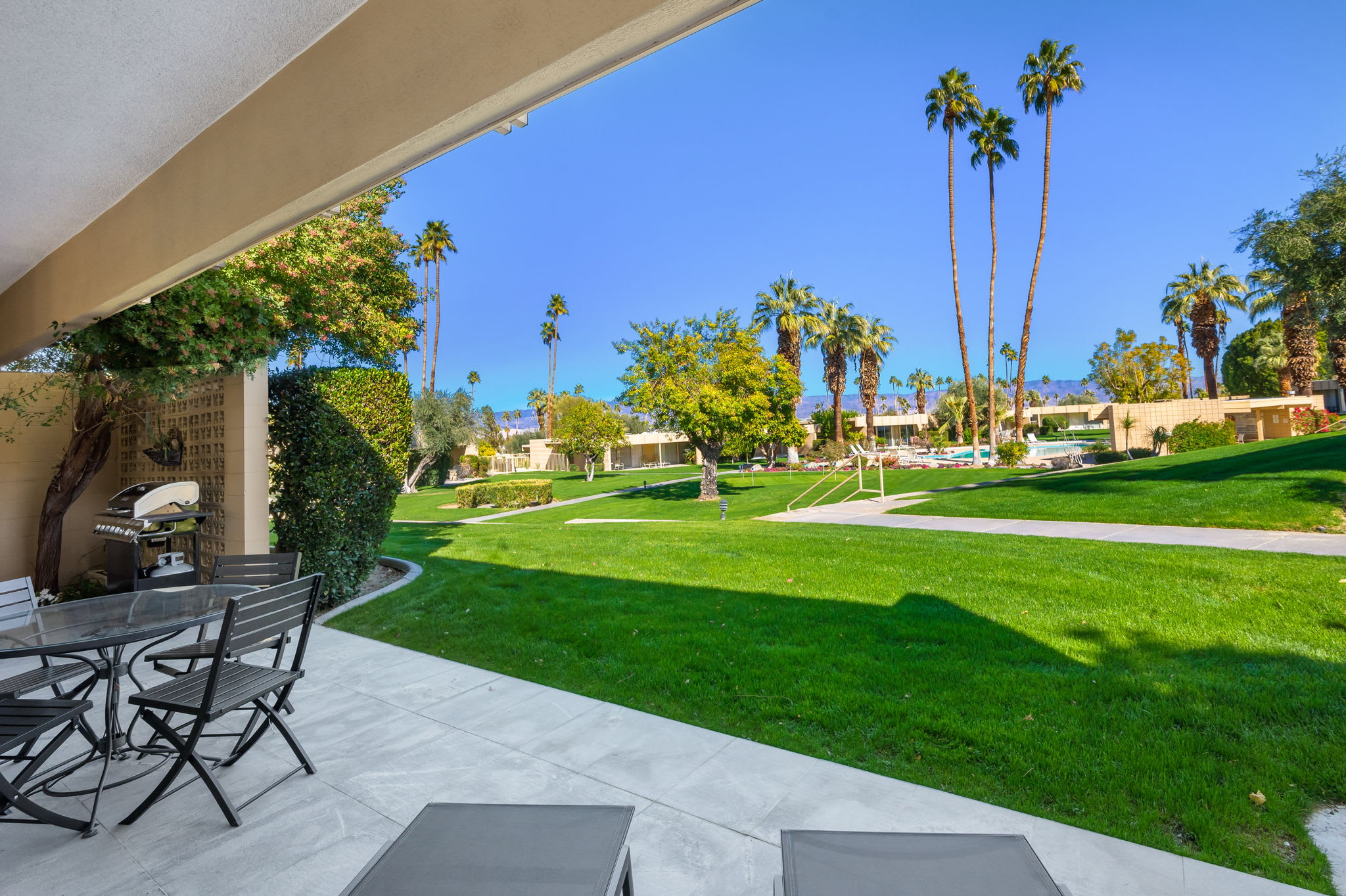 Outdoor dining beside the lawn and landscaped community grounds.