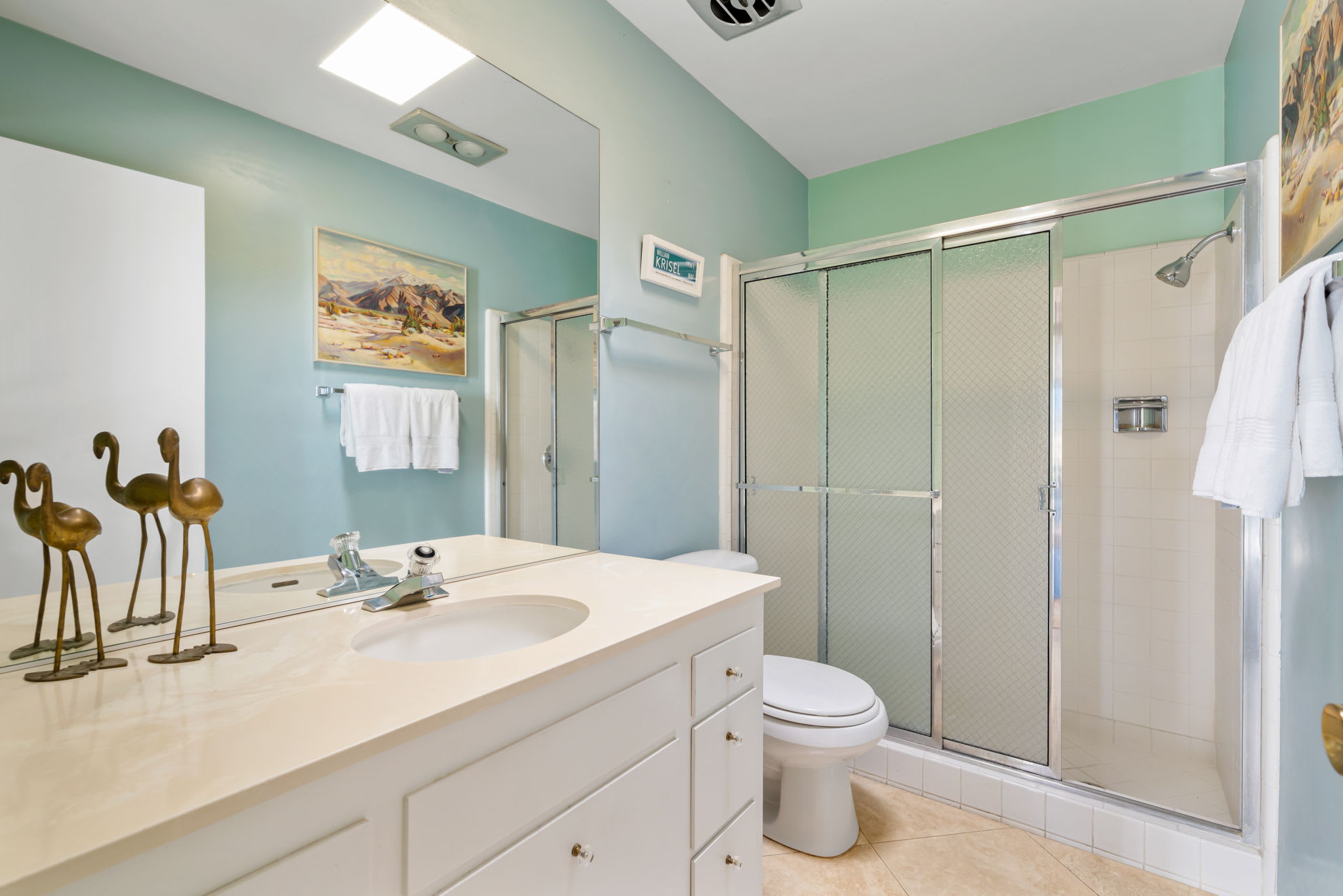 Bathroom vanity and glass shower beneath clerestory windows.