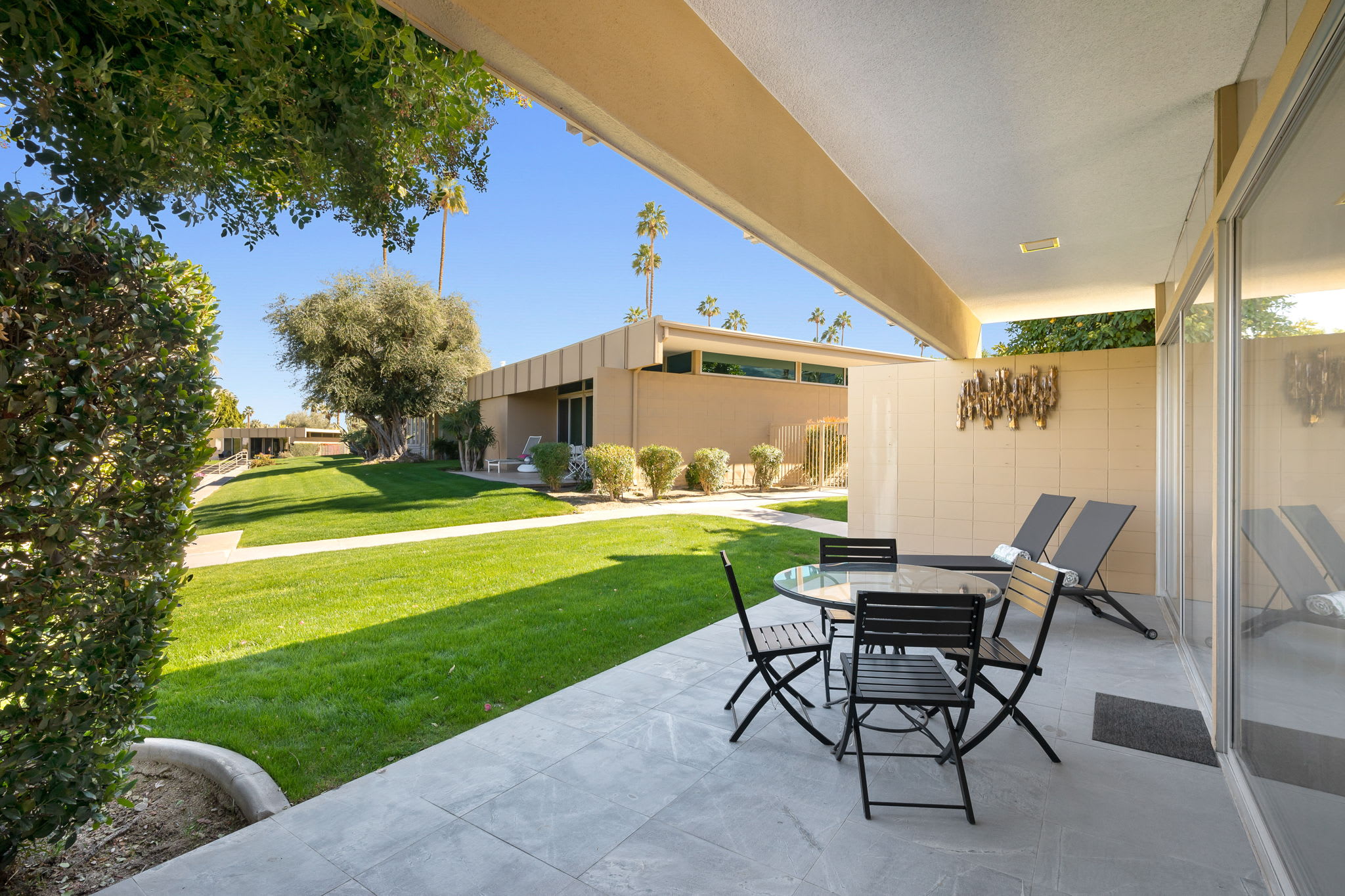Covered rear patio with a dining table beside the lawn.