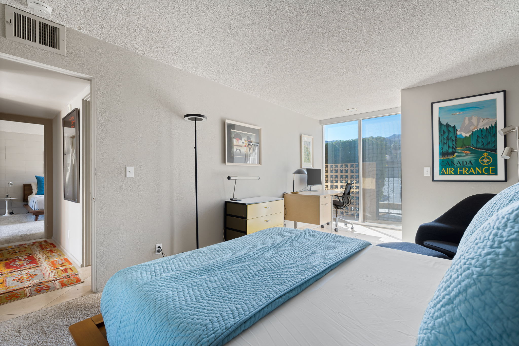 Bedroom with blue bedding and a sliding door overlooking the lawn.