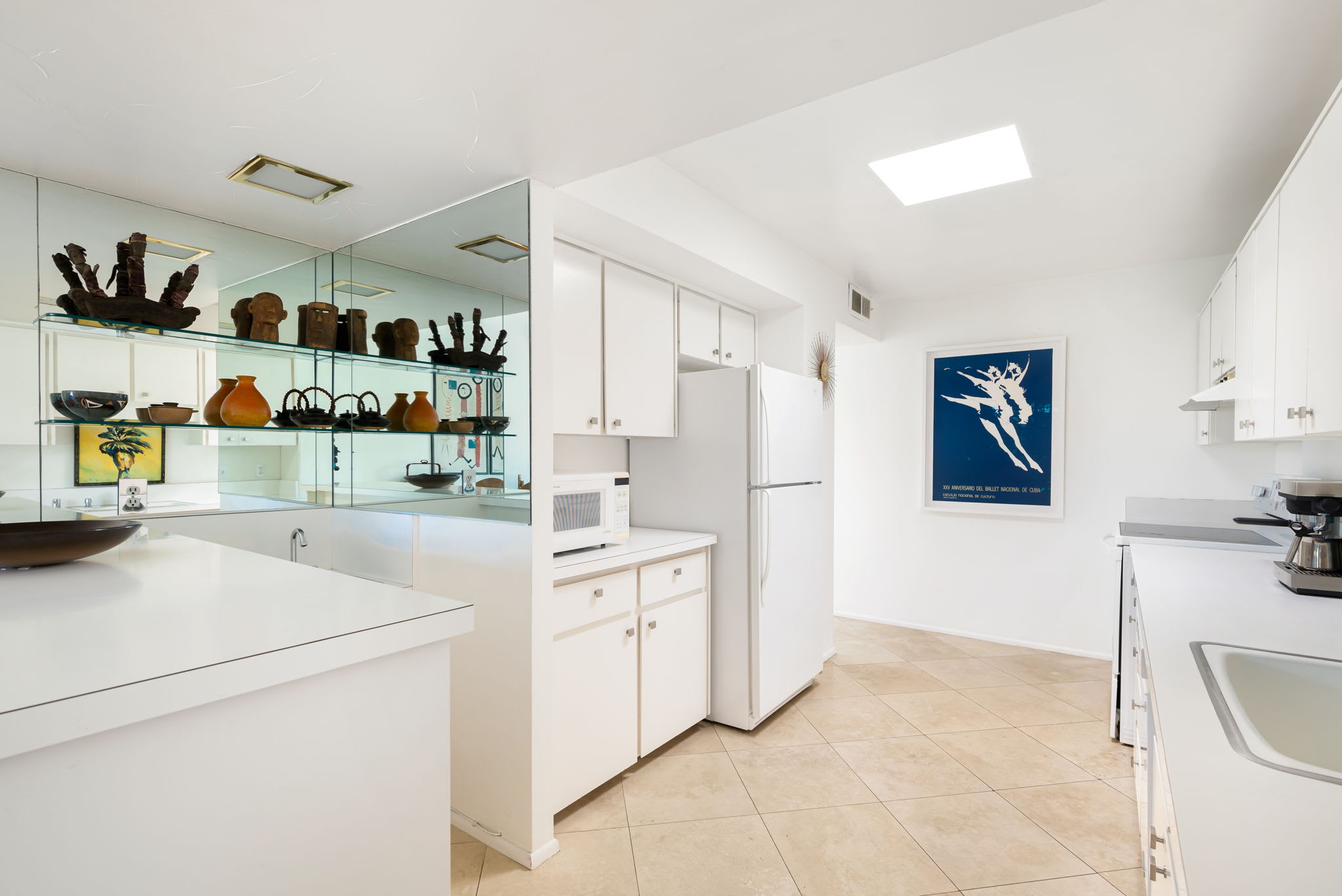 Kitchen island, white cabinetry and displayed glassware.