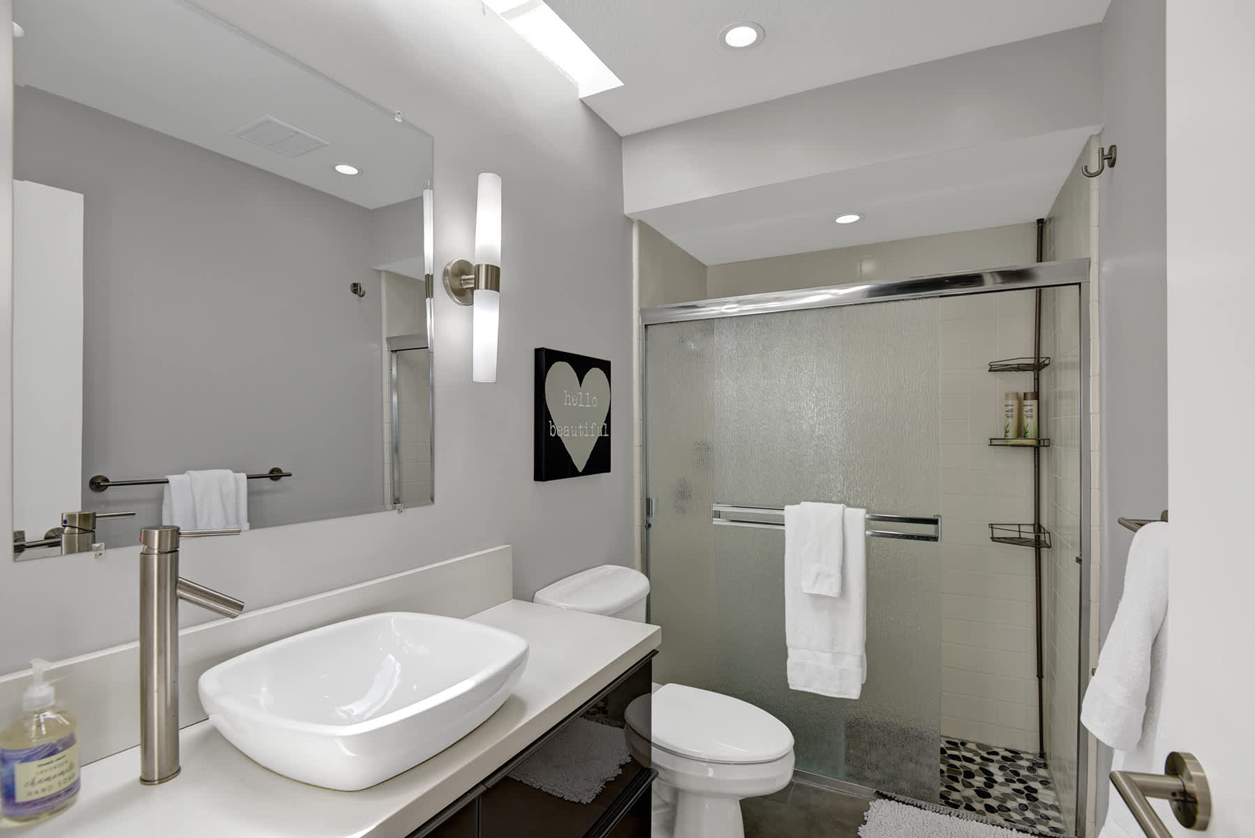 Bathroom with vessel sink, mirror and glass-enclosed shower.