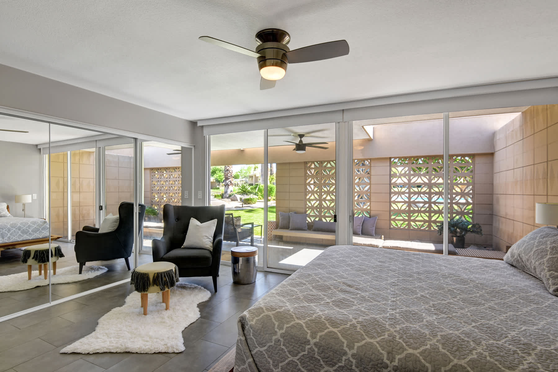 Bedroom view showing the bed, seating and broad windows.