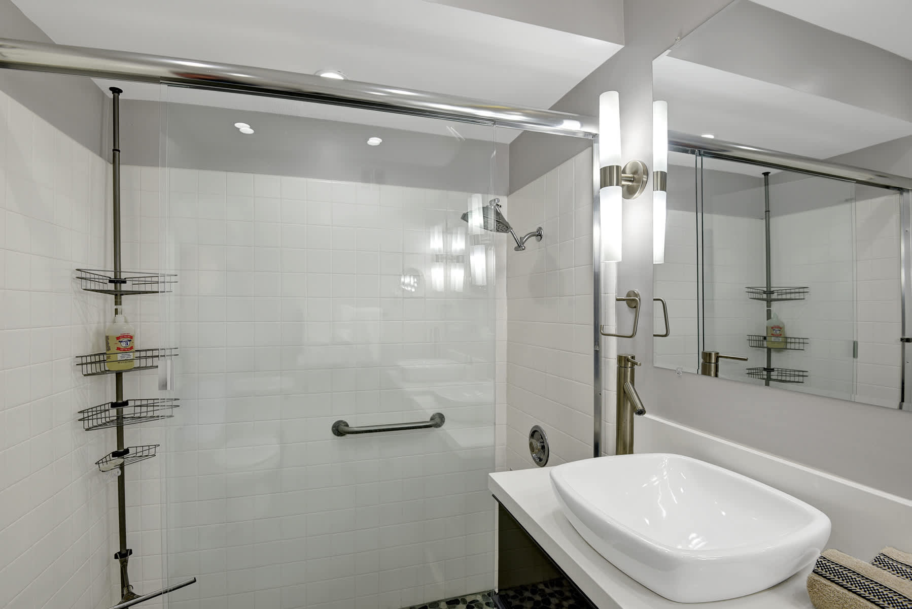 Glass-enclosed bathroom shower with tiled walls and built-in shelving.