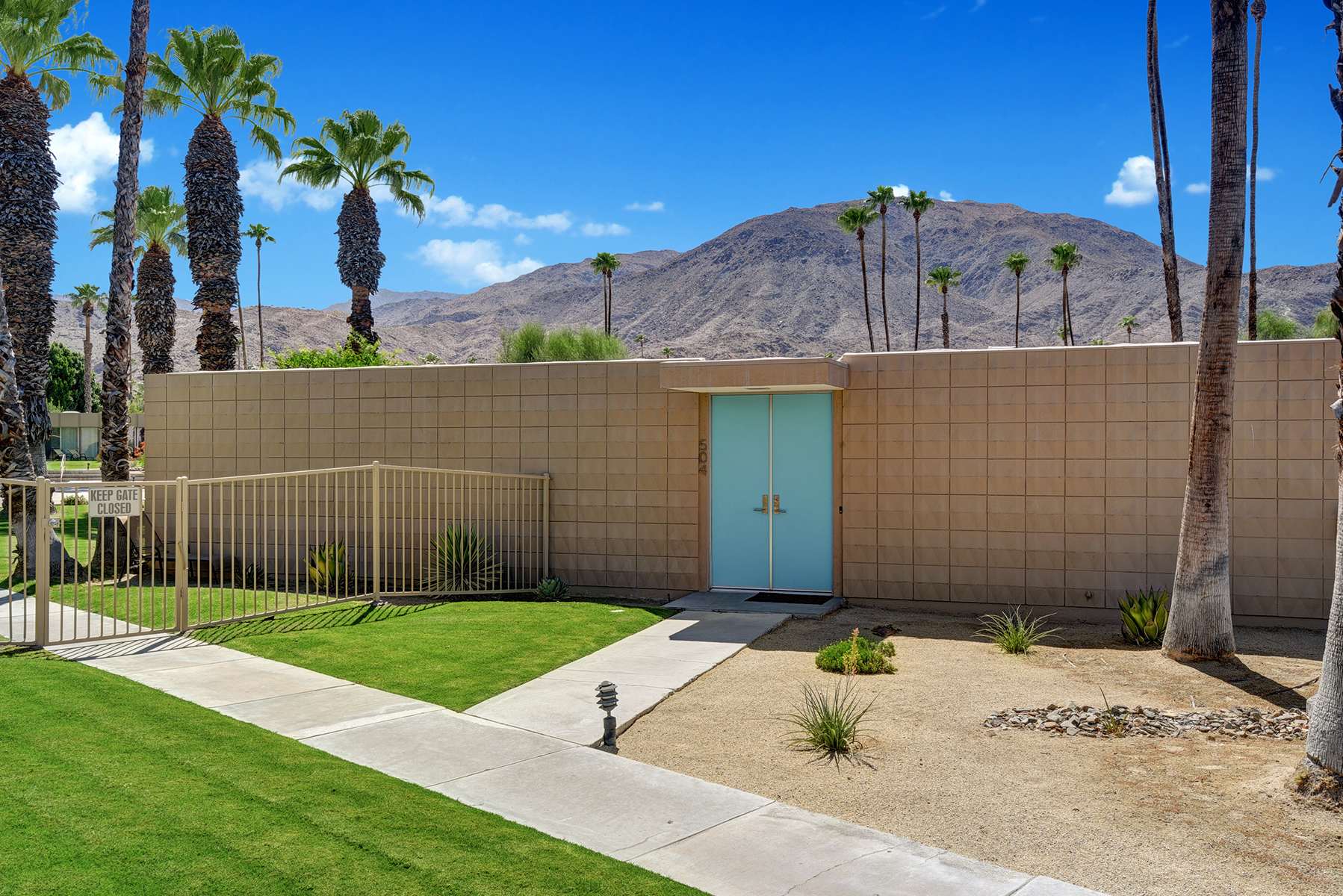 Exterior courtyard with lawn, concrete walkway and blue entry door.