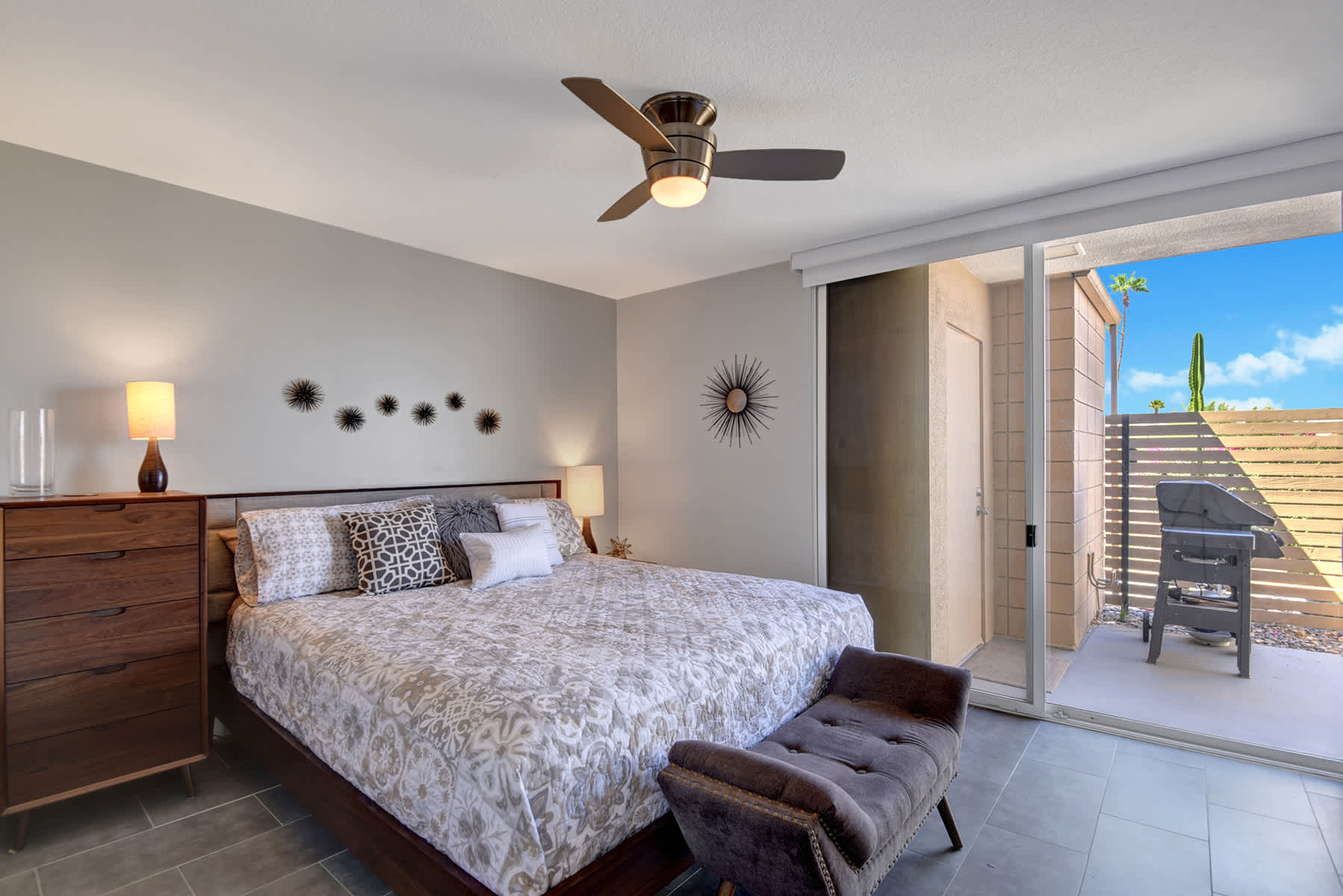 Bedroom with floral bedding, bedside furniture and sliding doors.