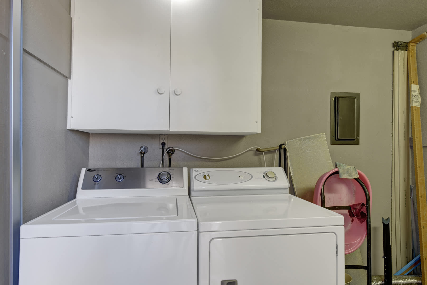 Laundry area with a washer, dryer and overhead storage cabinets.