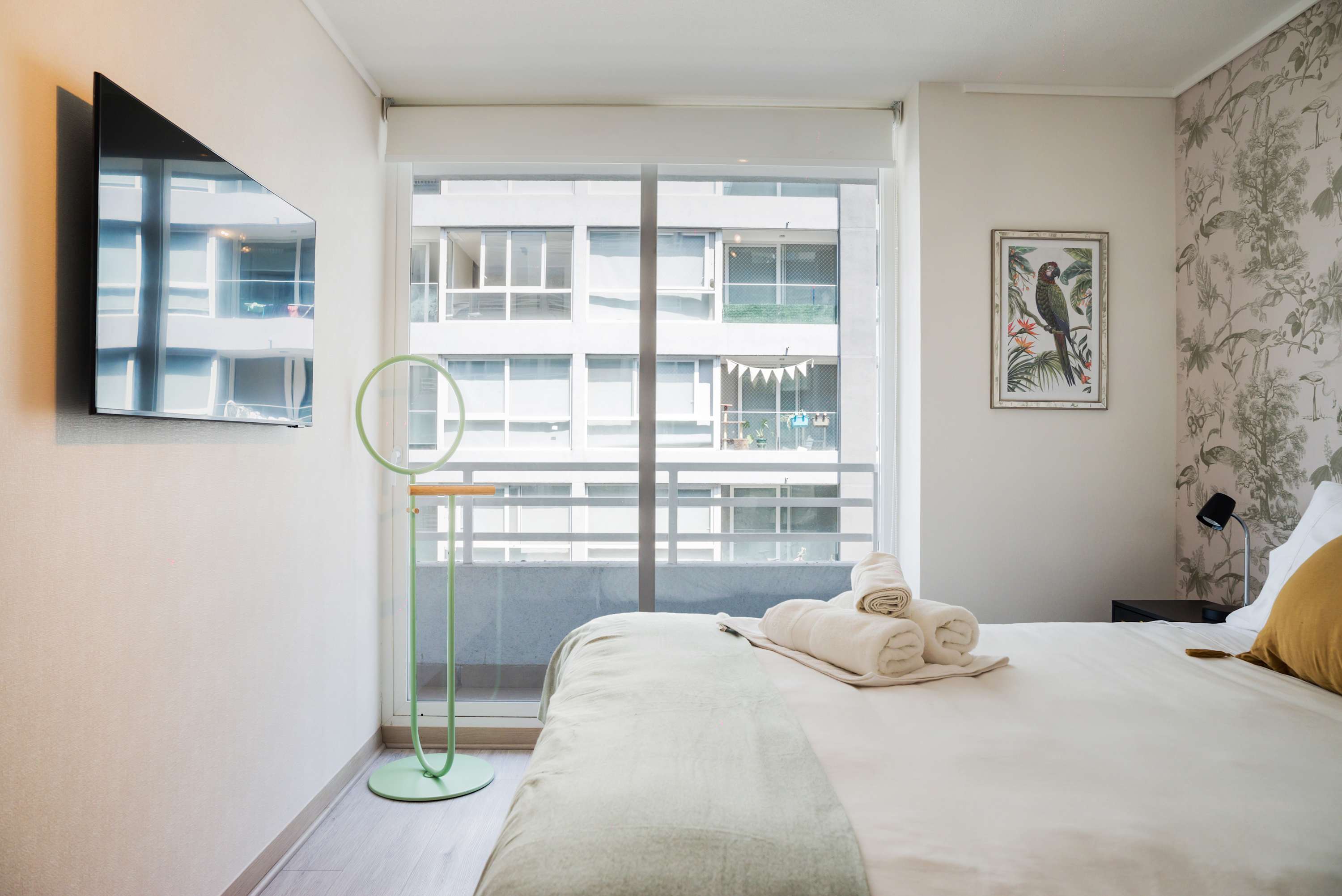 Relax in a cozy bedroom with modern decor and a view of the cityscape, perfect for unwinding after a day of exploring.