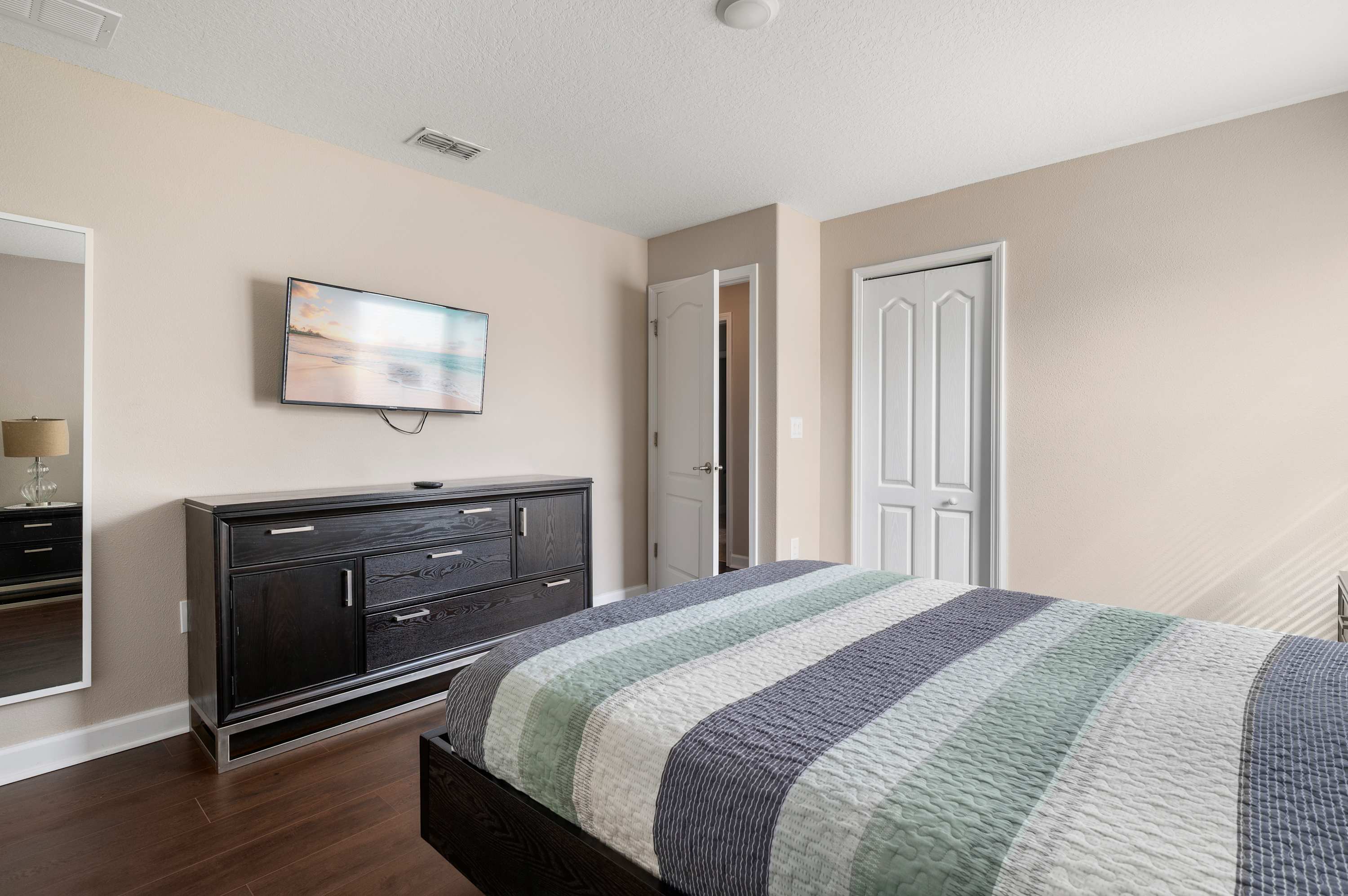 Relaxing bedroom w/ dresser storage, TV & soft neutral tones throughout