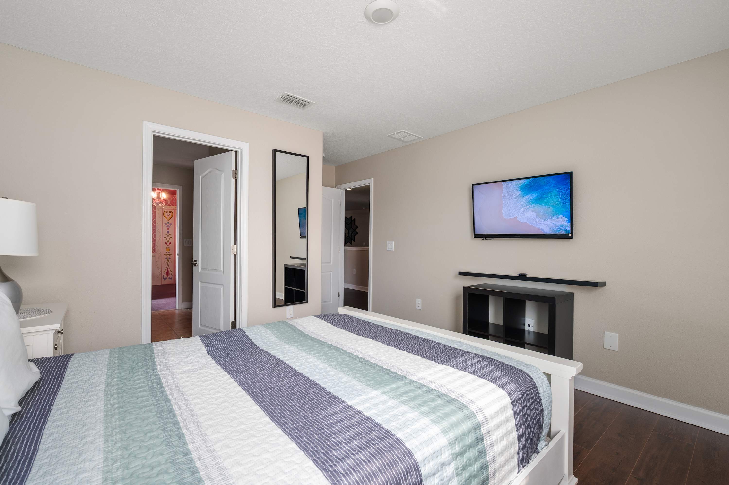 Spacious bedroom w/ TV, soft lighting & easy access to the nearby bath