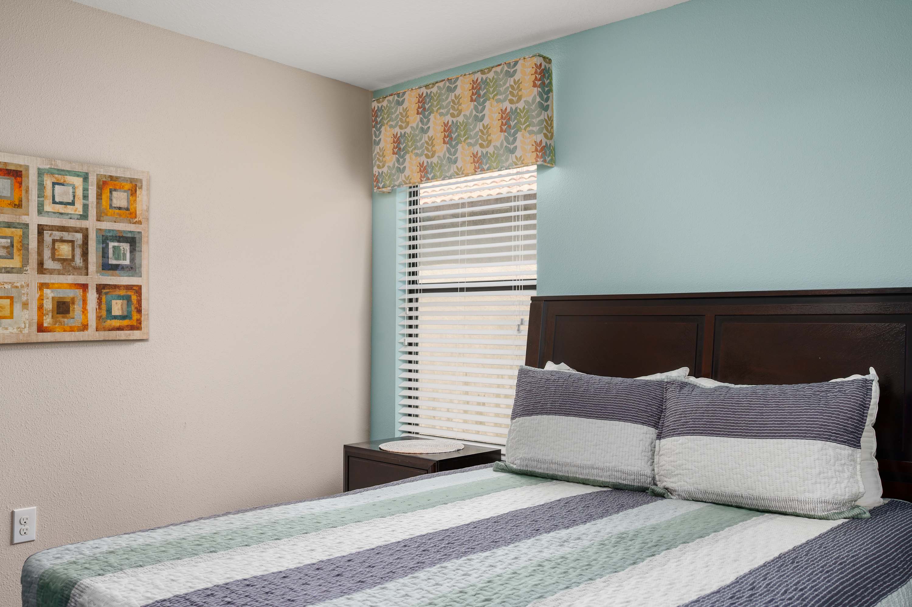 Cozy bedroom w/ soft blue walls, plush bedding & natural light throughout