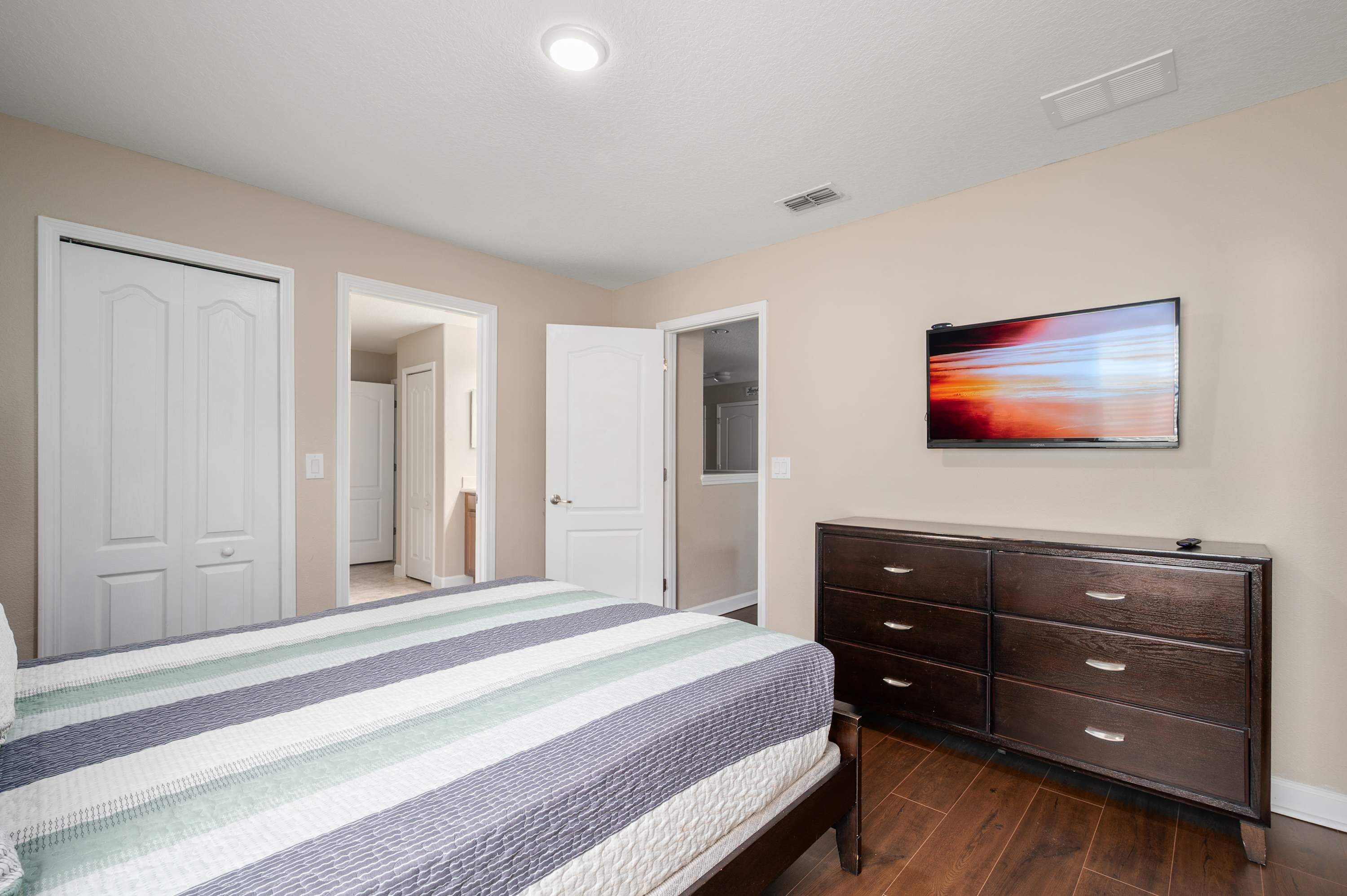 Relaxing bedroom w/ TV, dresser storage & calming neutral decor