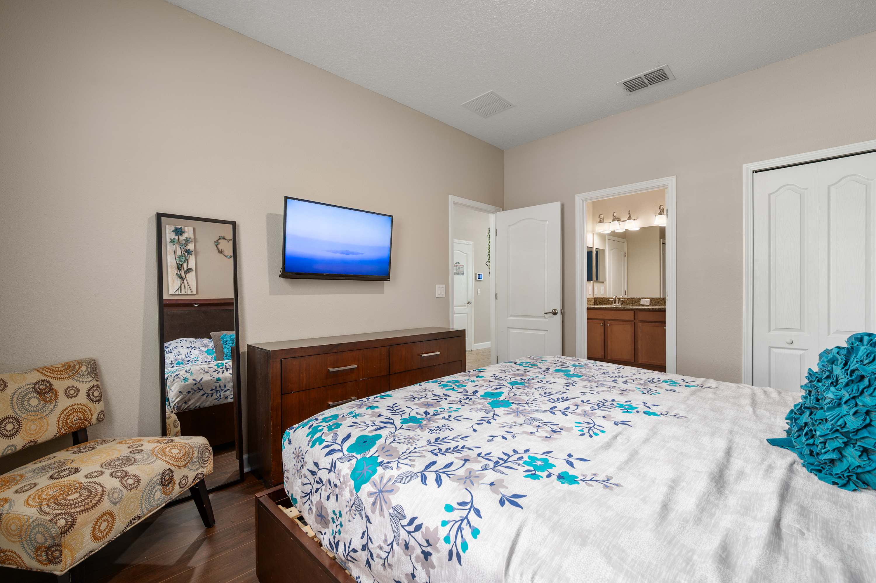 Spacious bedroom w/ TV, patterned bedding & easy access to nearby rooms
