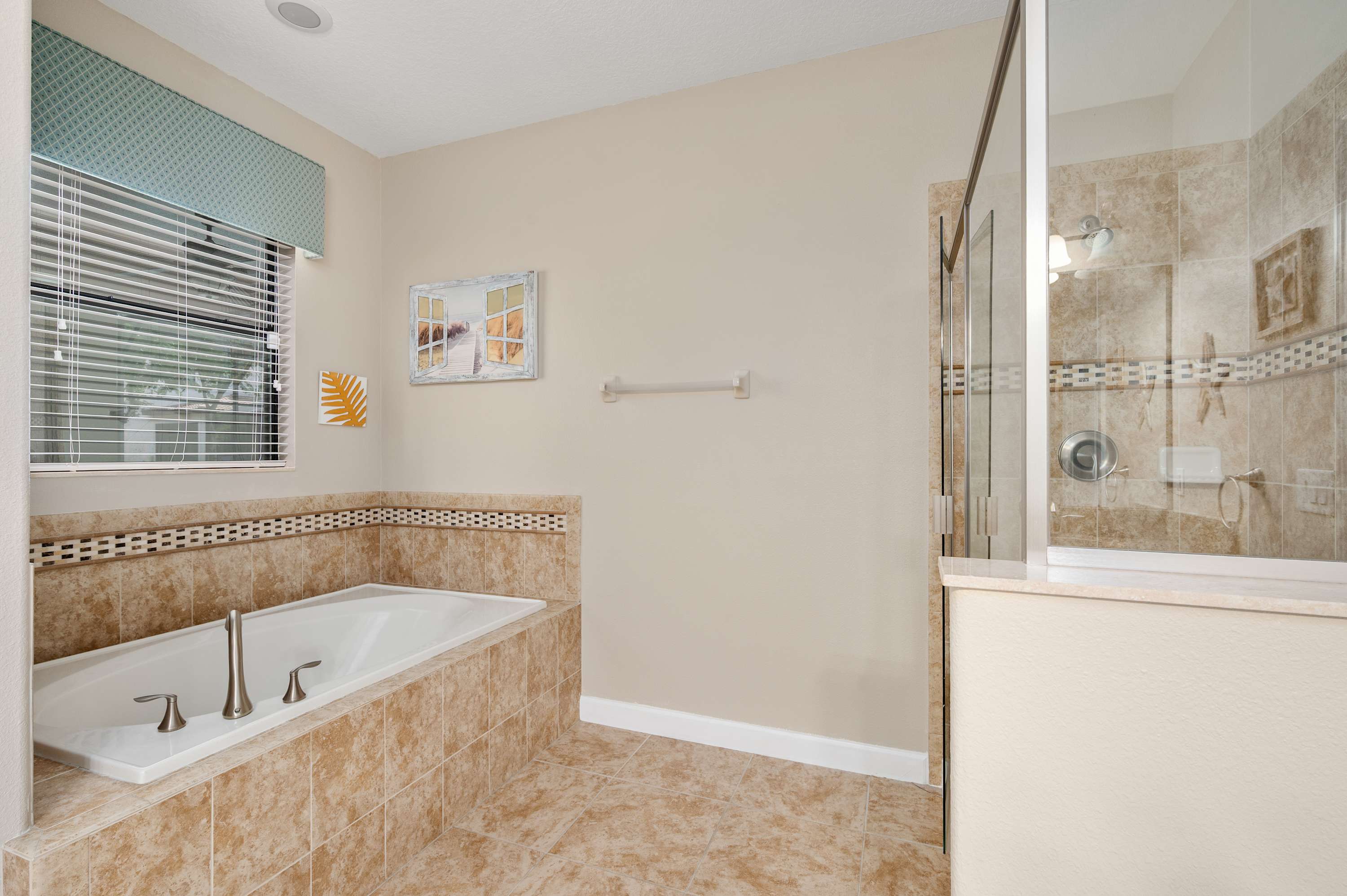 Spacious bathroom w/ soaking tub, large mirror & warm neutral tones