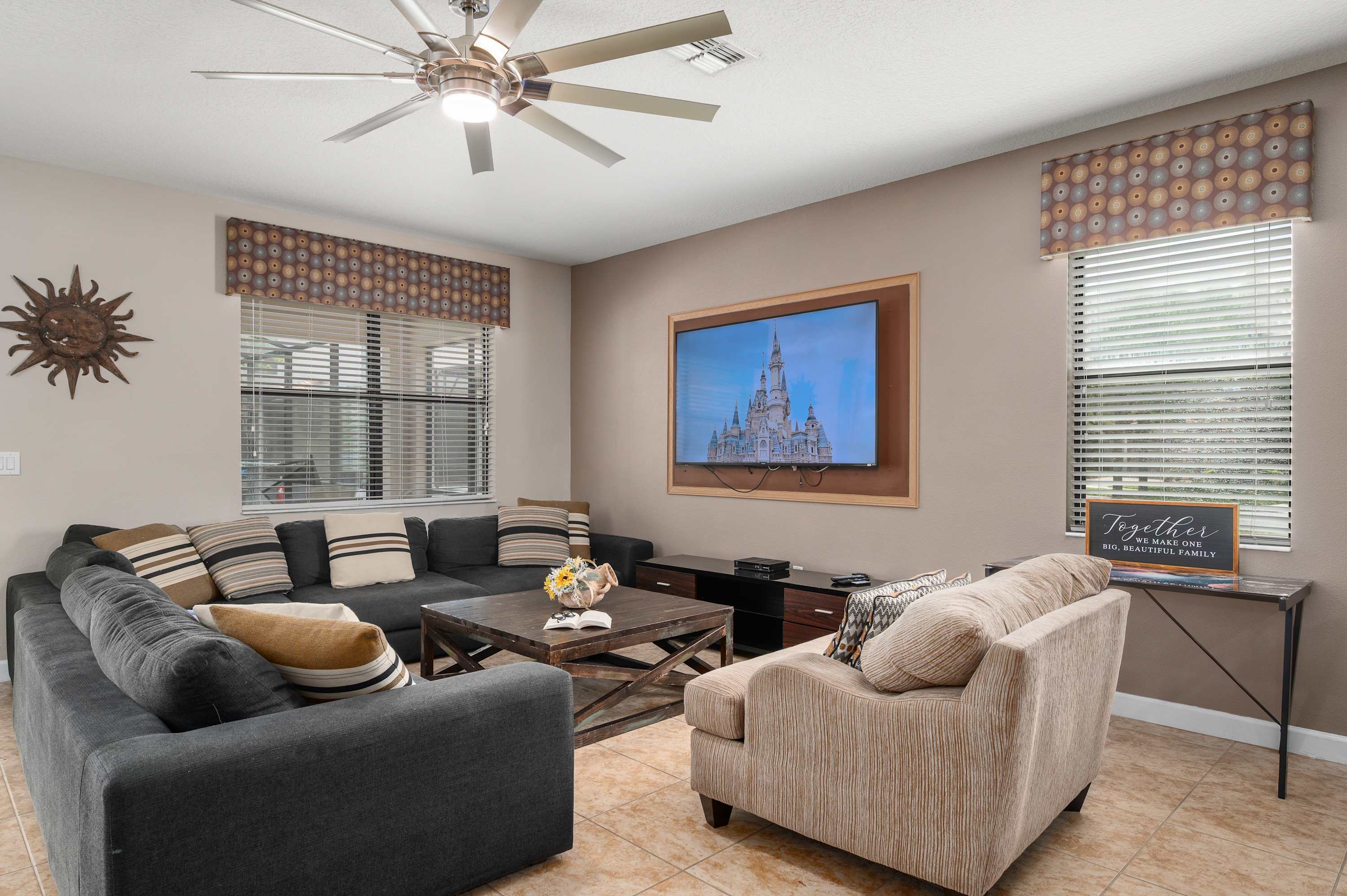 Cozy living room w/ plush seating, large TV & windows bringing in natural light