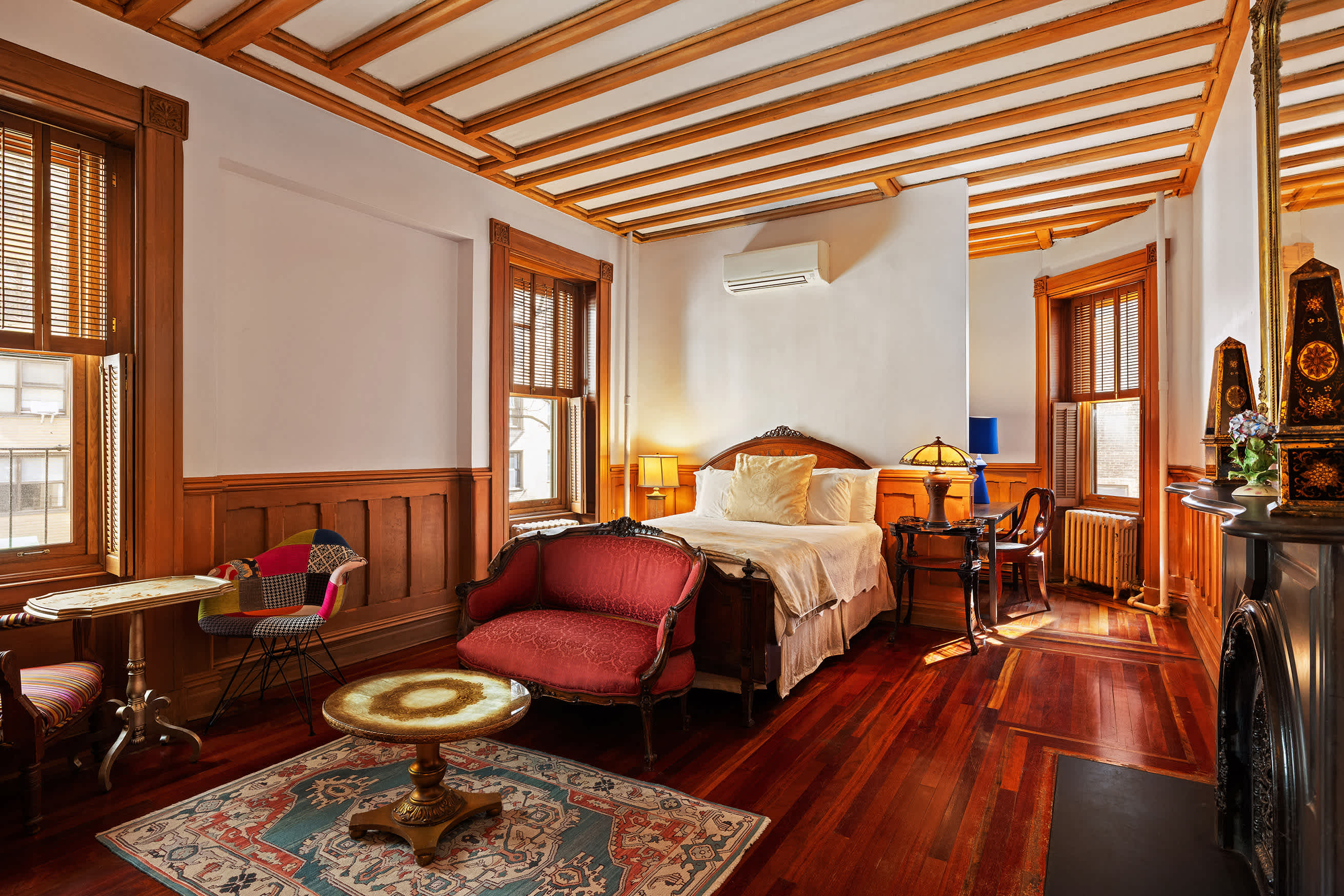 A wide view of a cozy hotel room with a bed, sofa, and fireplace.