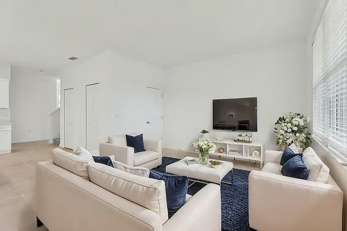 Relax in this stylish, sunlit living room with plush seating and a large TV, perfect for unwinding after a day of adventure.