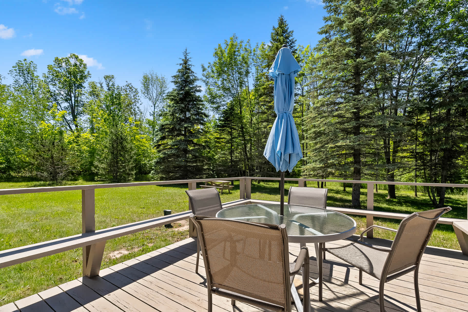 Large outdoor deck includes a table and chairs, and a propane grill