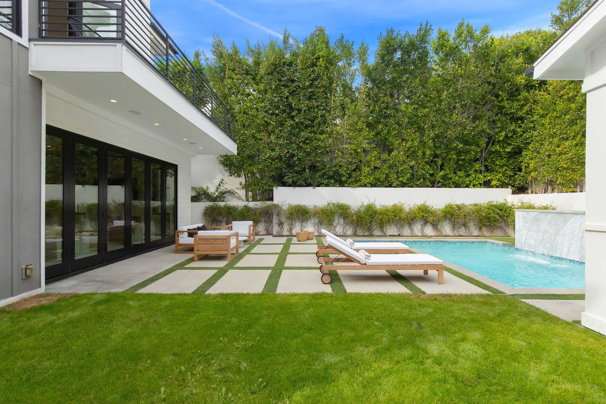 A private West Hollywood backyard with pool, lawn, lounge areas, and direct access from the living space