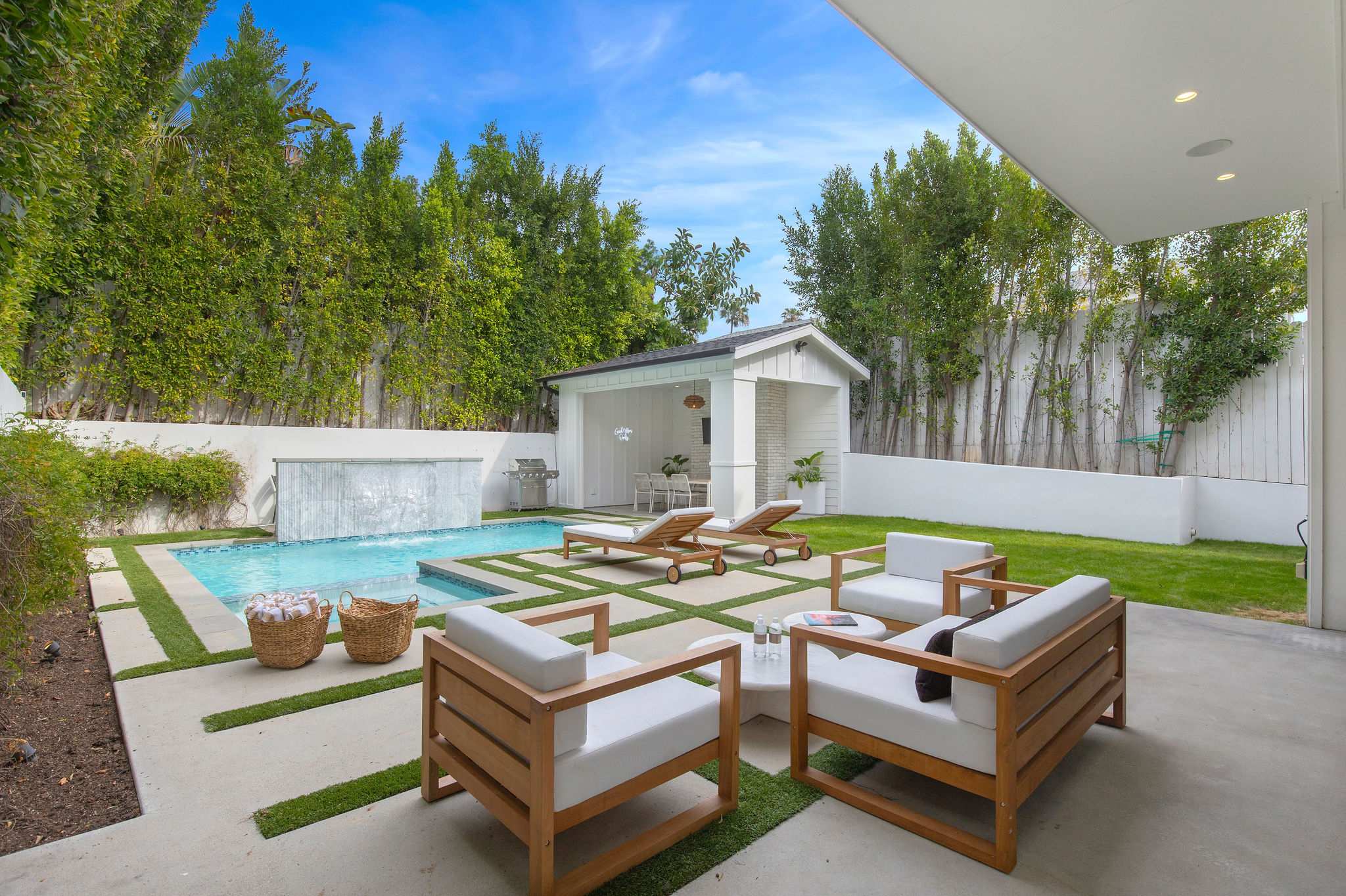 A private backyard lounge in West Hollywood with poolside seating, cabana, and landscaped privacy