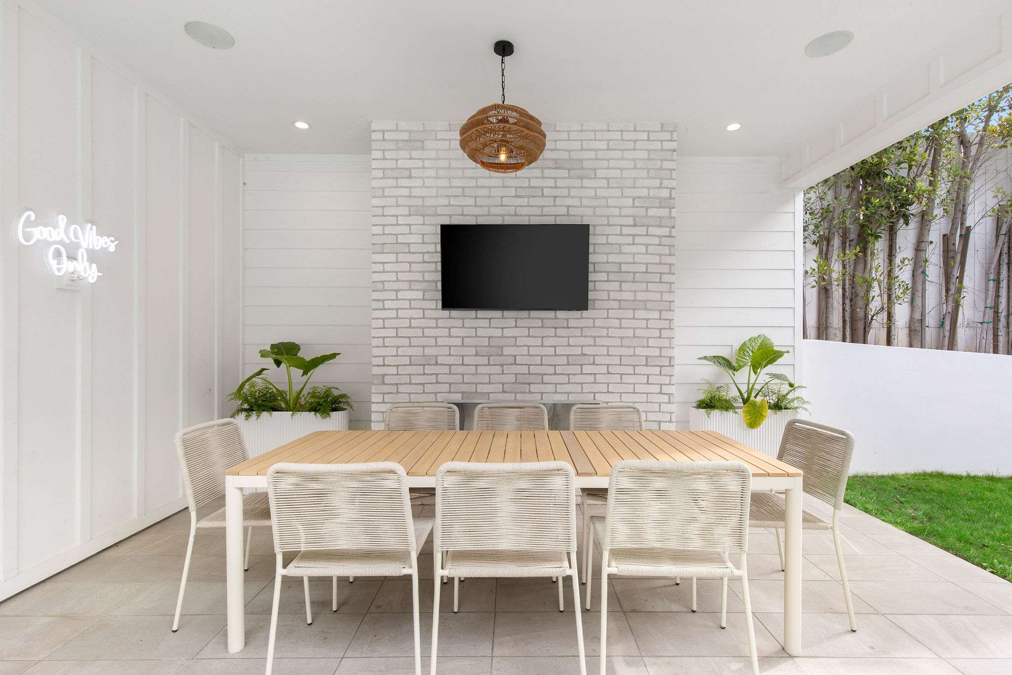 Covered outdoor dining in West Hollywood with fireplace, poolside seating, and entertaining space