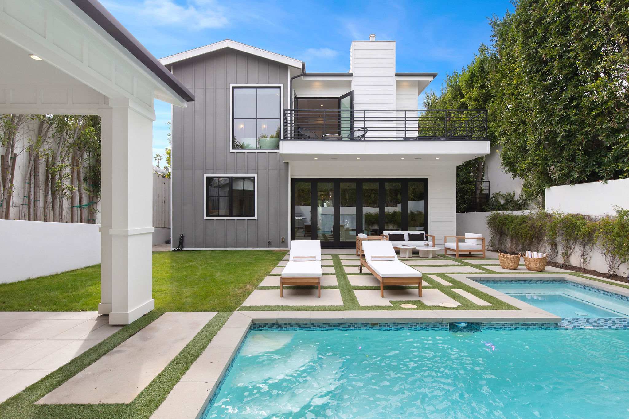 A resort-style pool in West Hollywood framed by modern farmhouse architecture and landscaped privacy