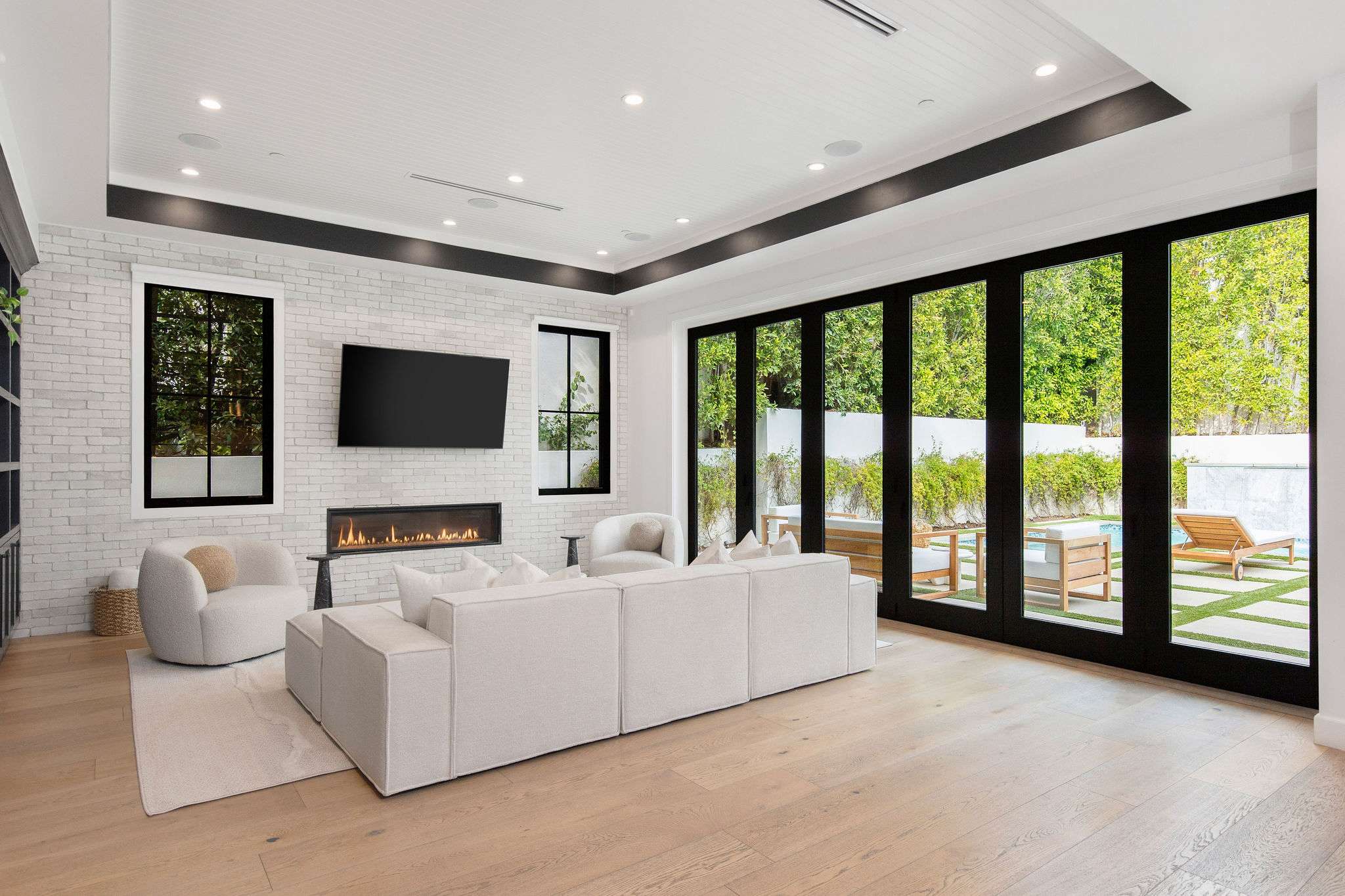A light-filled living room with fireplace feature wall and full-height glass opening to the backyard