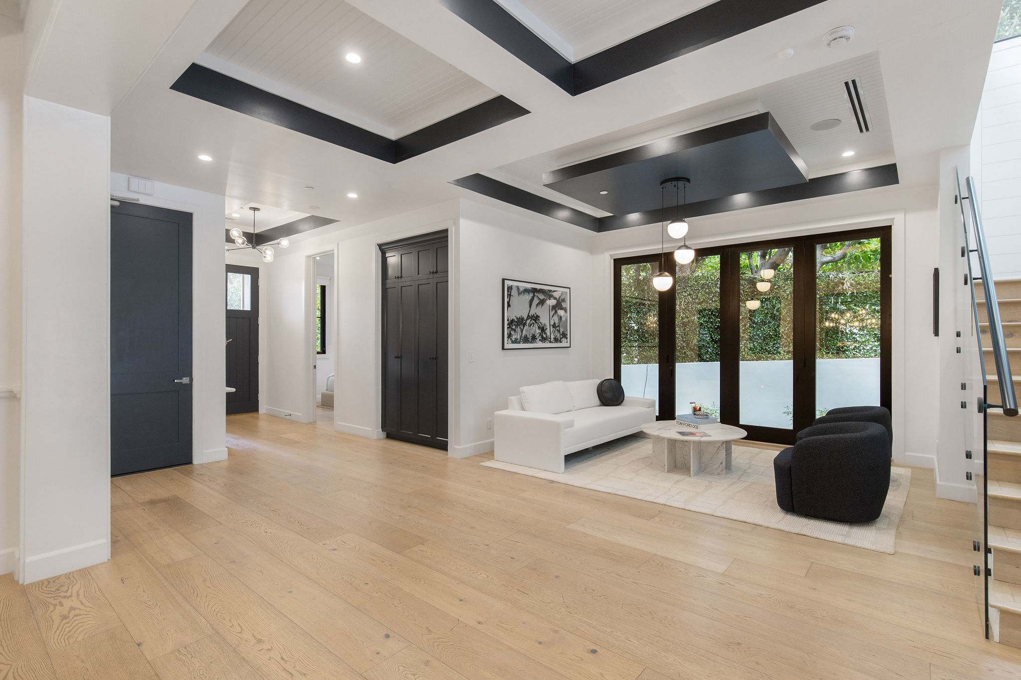 A grand entry living space with high ceilings, wide-plank floors, and modern architectural detailing
