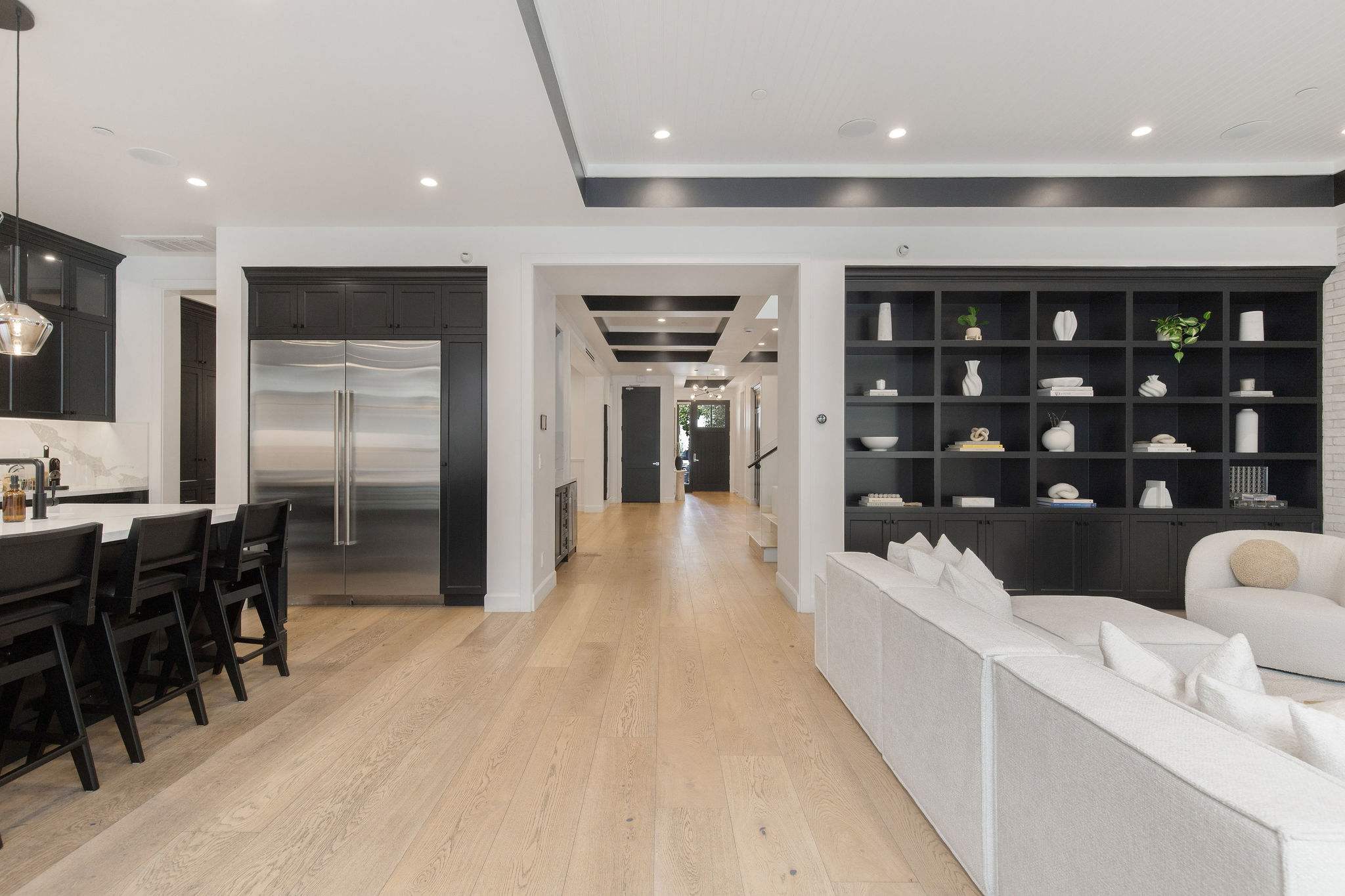 Open-concept living and kitchen layout with built-in shelving, wide-plank floors, and seamless flow